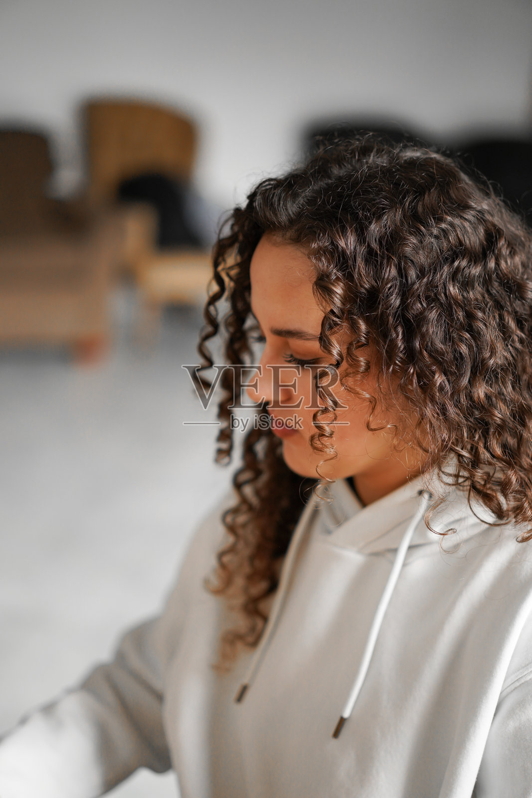 一位卷发女性坐在钢琴前，享受着音乐。照片摄影图片