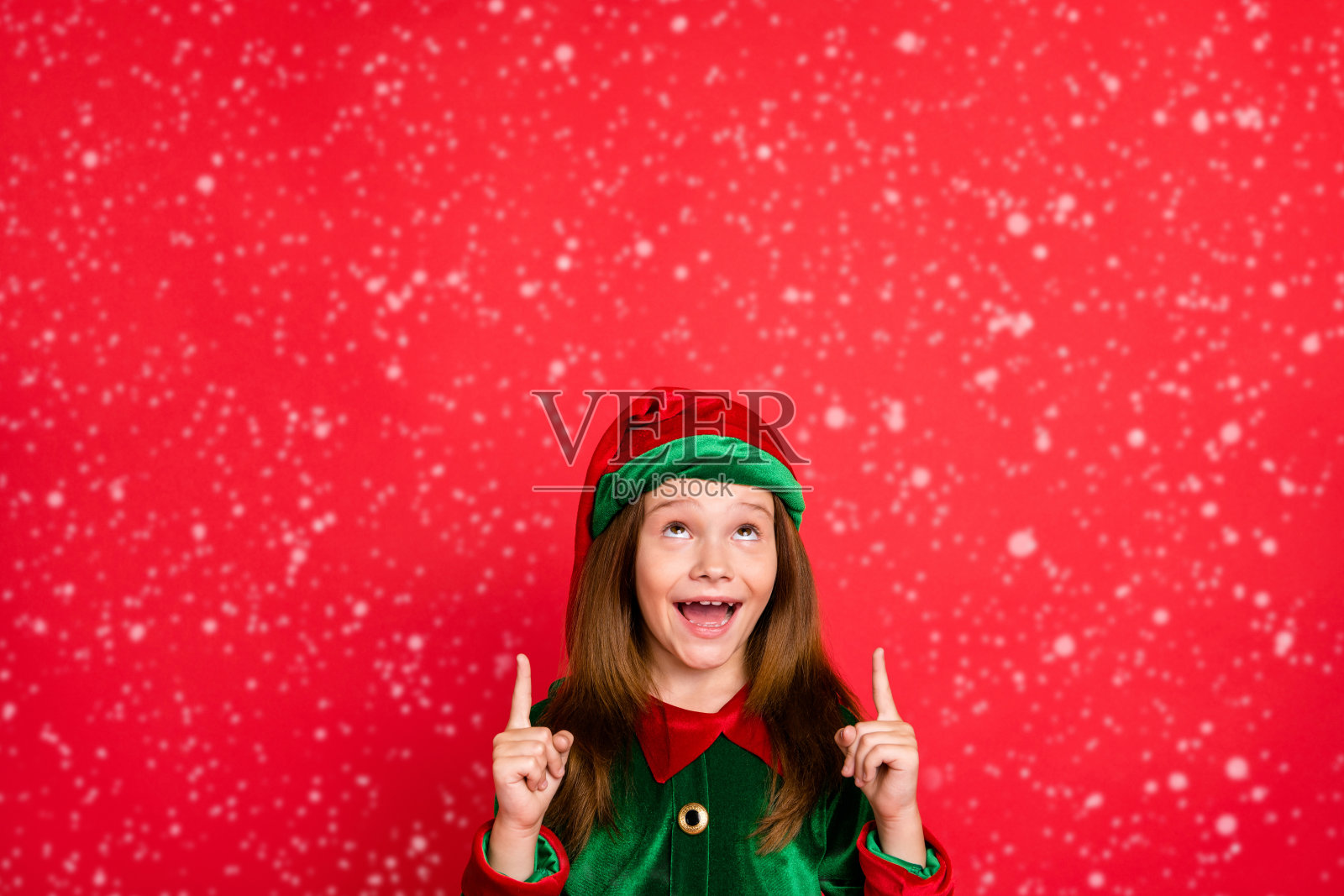 佩戴帽子的惊讶精灵小孩，惊呼“哇哦，天哪”，用食指指向广告，背景为红色。照片摄影图片