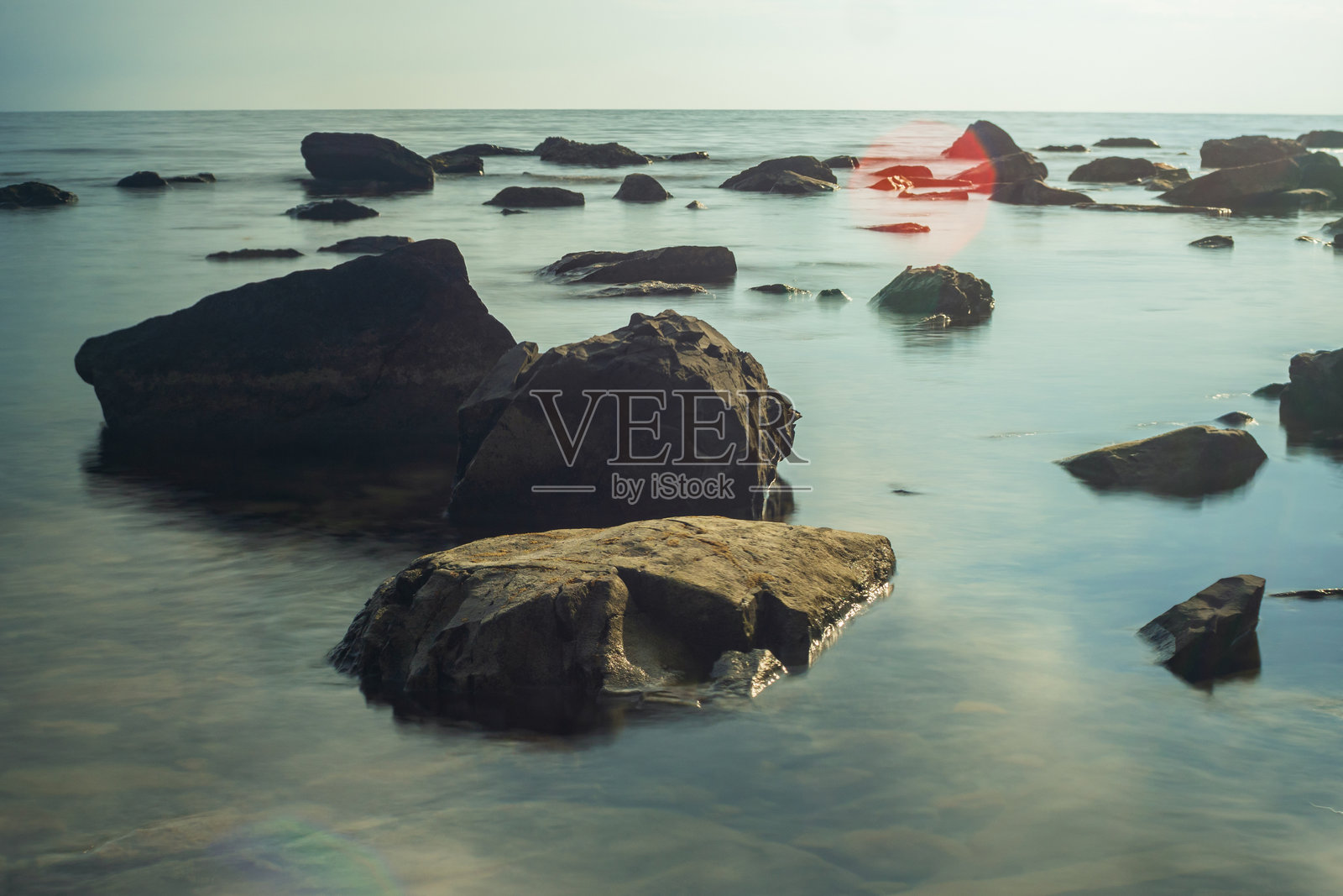 海水中的石头。长时间曝光使水的运动变得模糊。照片摄影图片