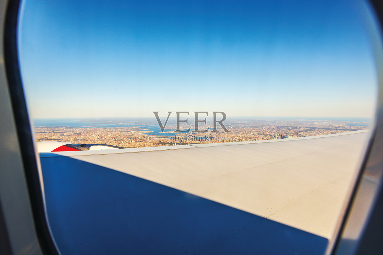 从飞机窗户俯瞰曼哈顿城市景观和海岸，机翼在晴空下。纽约，美国。照片摄影图片