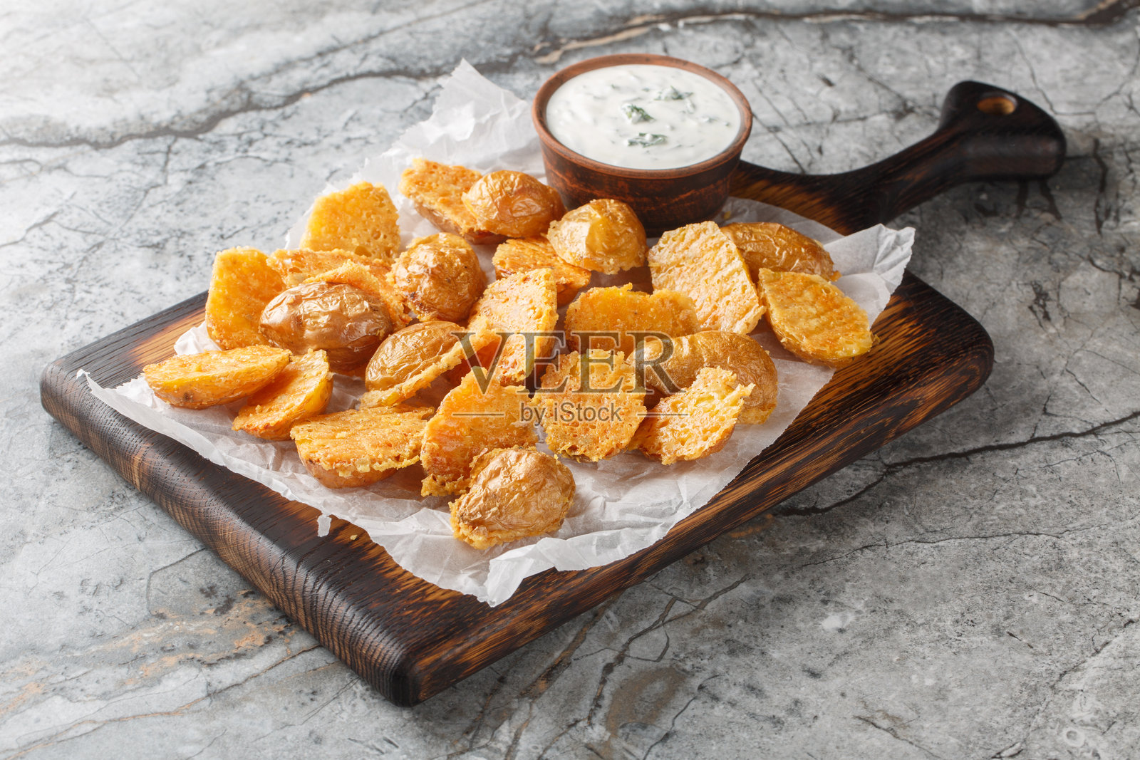 脆皮开胃小吃：帕尔马奶酪婴儿土豆配酸奶油蘸酱，特写在烘焙纸上。横向排列。照片摄影图片