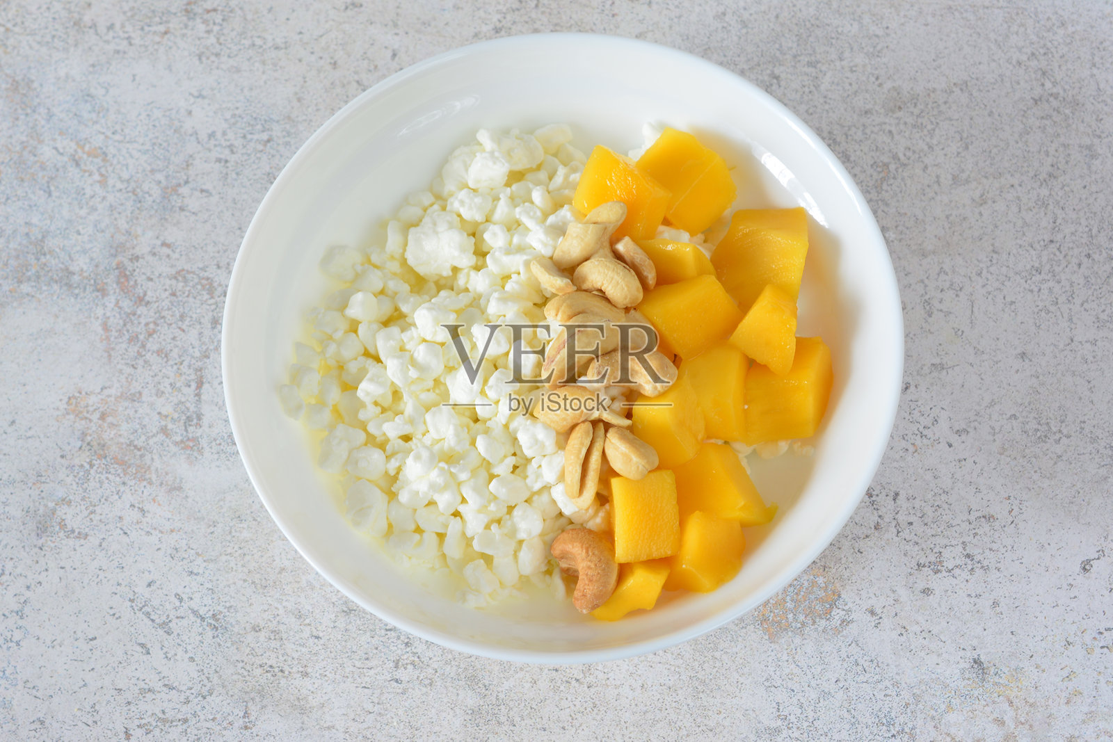 一碗从上方看去的奶酪、芒果和坚果照片摄影图片