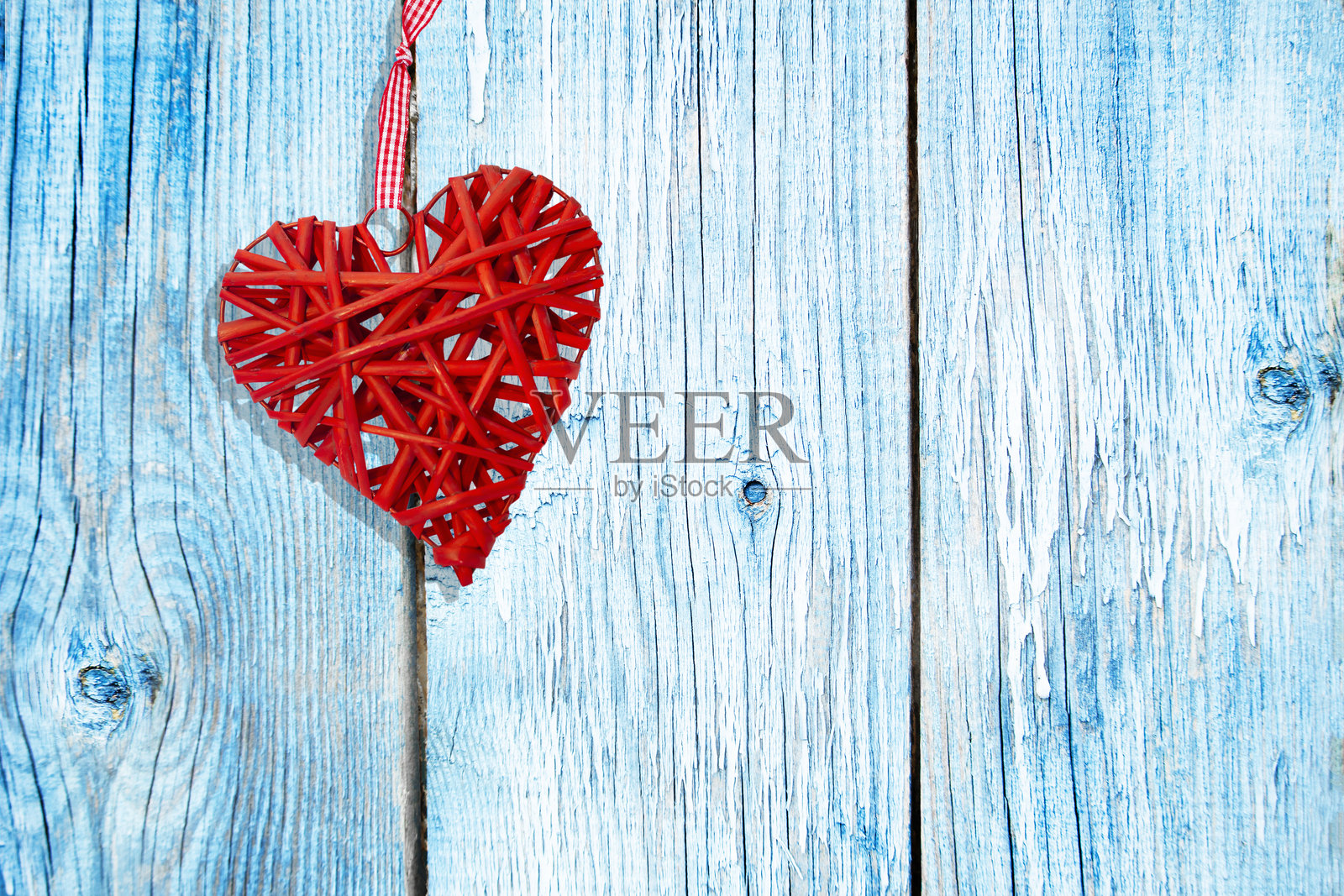 蓝色木背景上的红色藤编心形装饰。乡村风格。情人节照片摄影图片