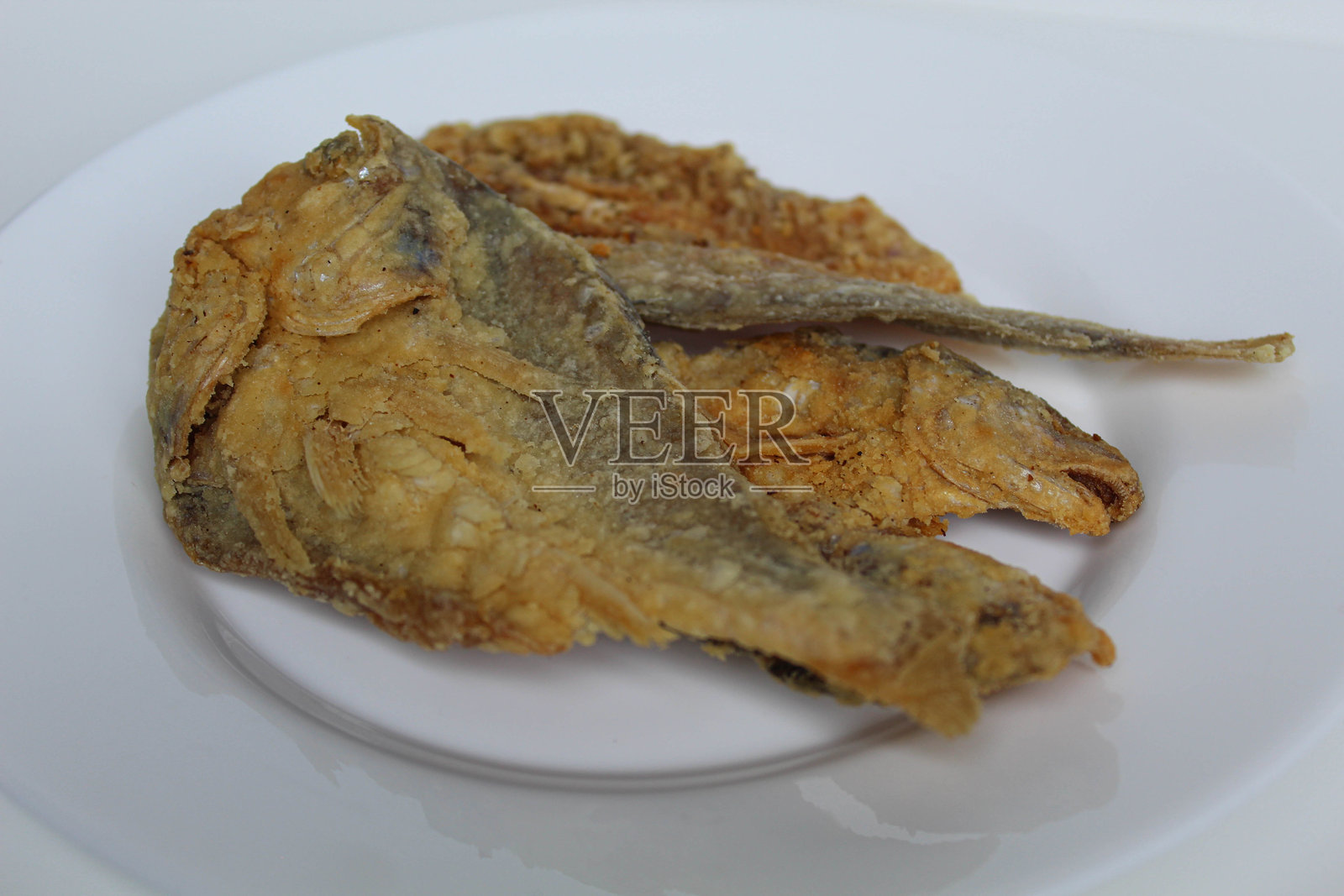 炸鱼。用盐腌制的鱼，切成两半，裹上面粉，在印度尼西亚称为Gereh或Ikan Asin。背景为白色。照片摄影图片
