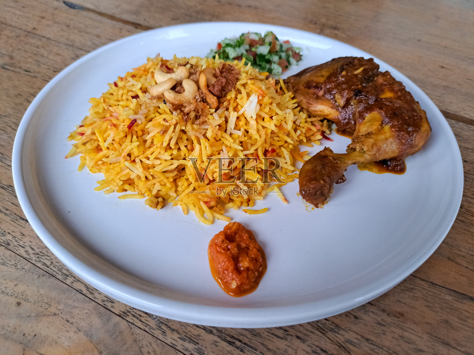 美味的鸡肉香饭或鸡肉炖饭，配有炸洋葱、腌制品、腰果和辣椒酱。中东美食菜单。照片摄影图片