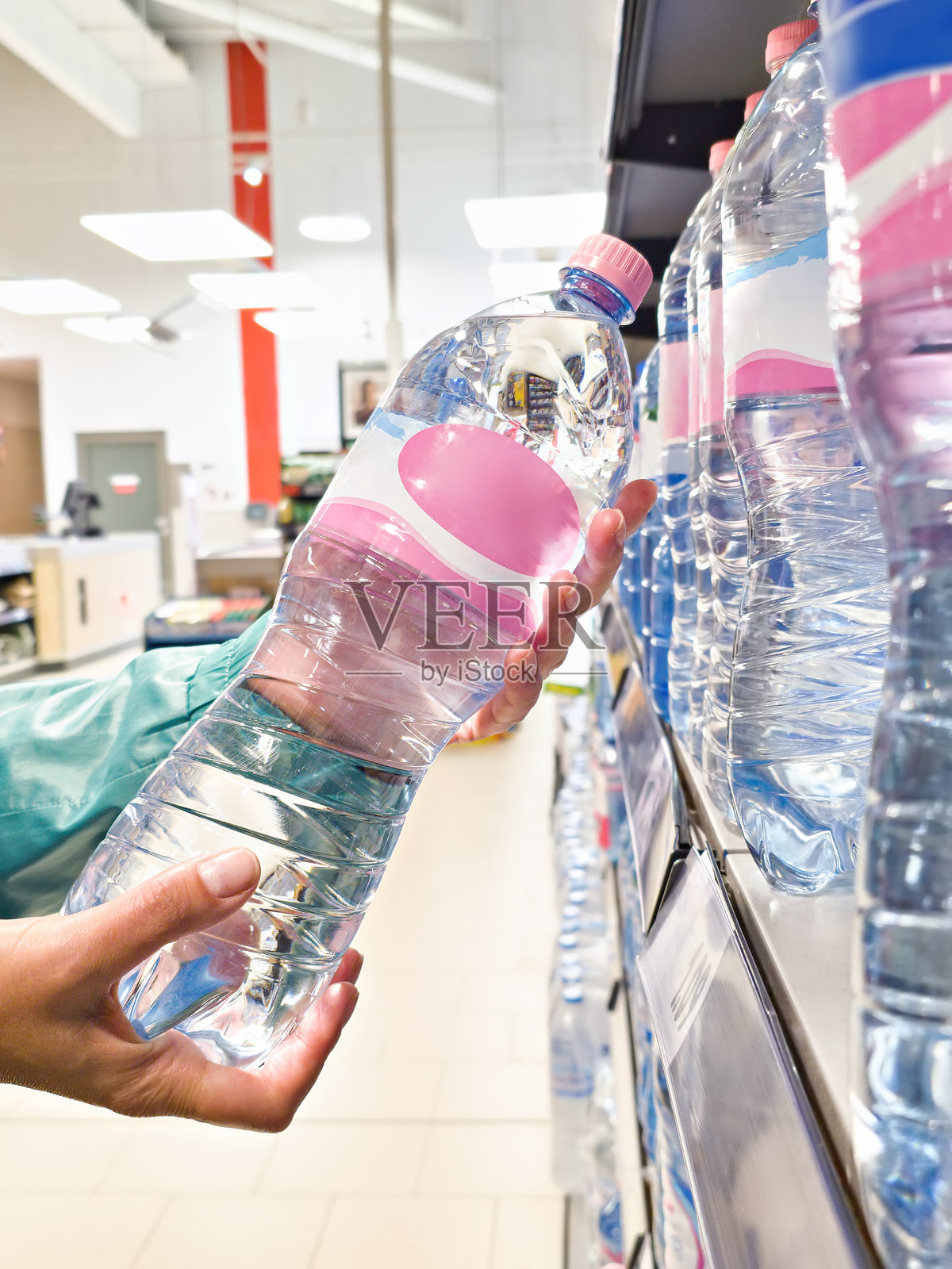手中拿着一瓶饮用水在商店里照片摄影图片