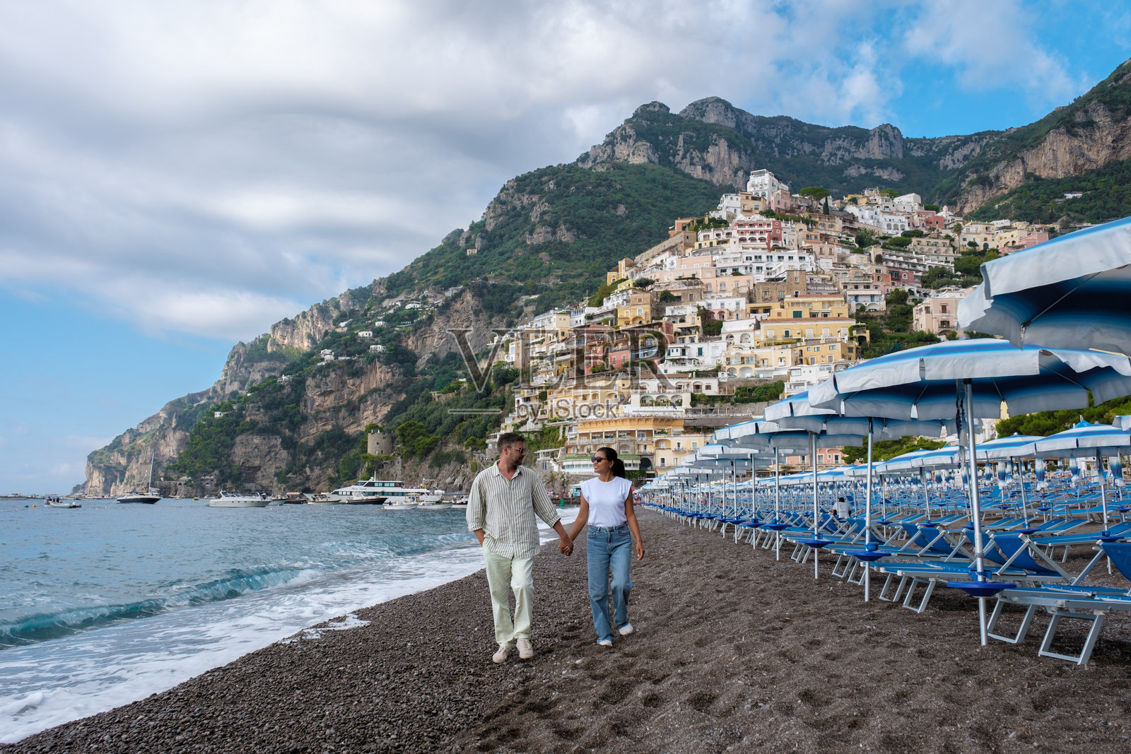 一对情侣手牵手走在意大利阿马尔菲海岸的波西塔诺沙滩上照片摄影图片