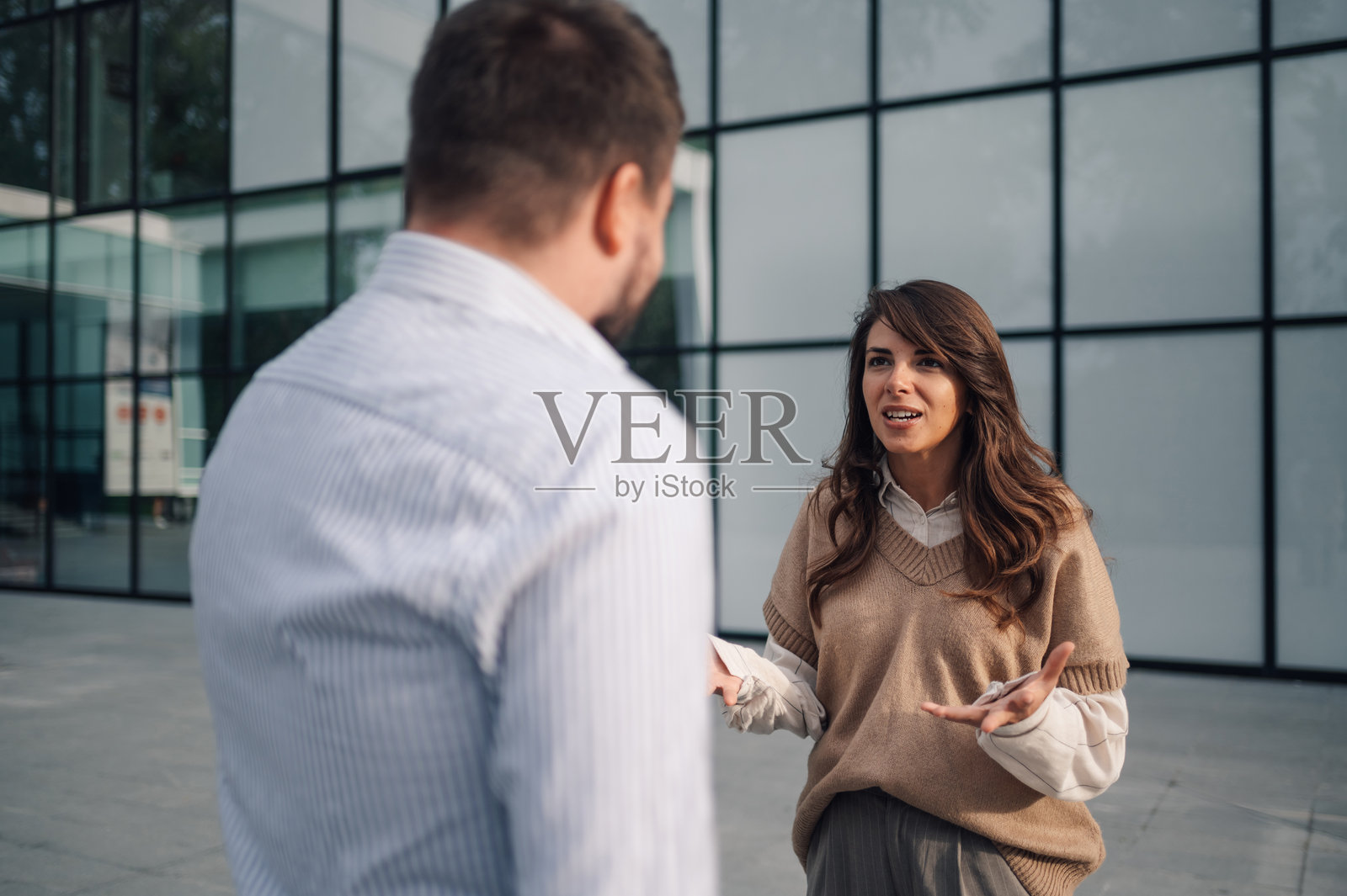 女商人在办公大楼前向她的男性同事解释某事。照片摄影图片