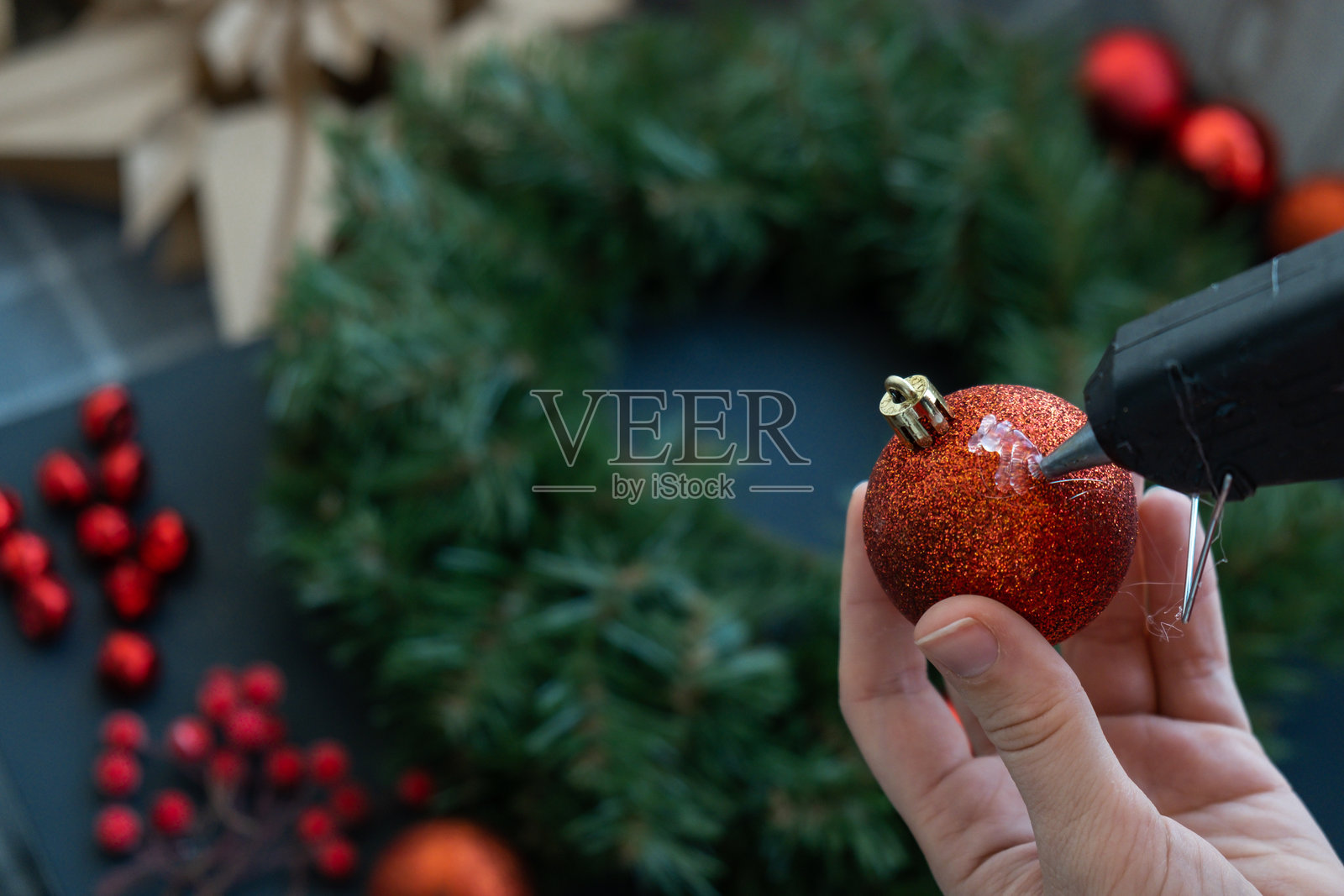 女性工匠使用热熔胶进行DIY，制作红色装饰的圣诞布置。小型企业，自雇创业者，自主职业。手工艺制作教程系列。零废弃环保冬季节日装饰。照片摄影图片