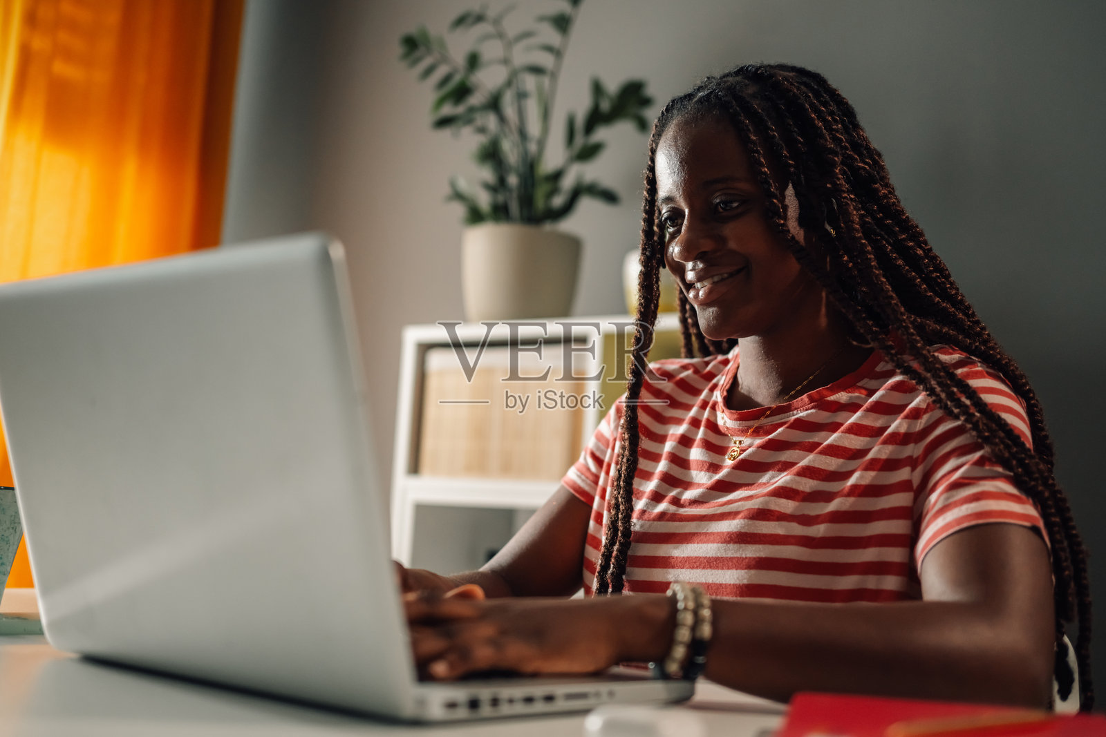 年轻的黑人女性在家办公，使用笔记本电脑照片摄影图片