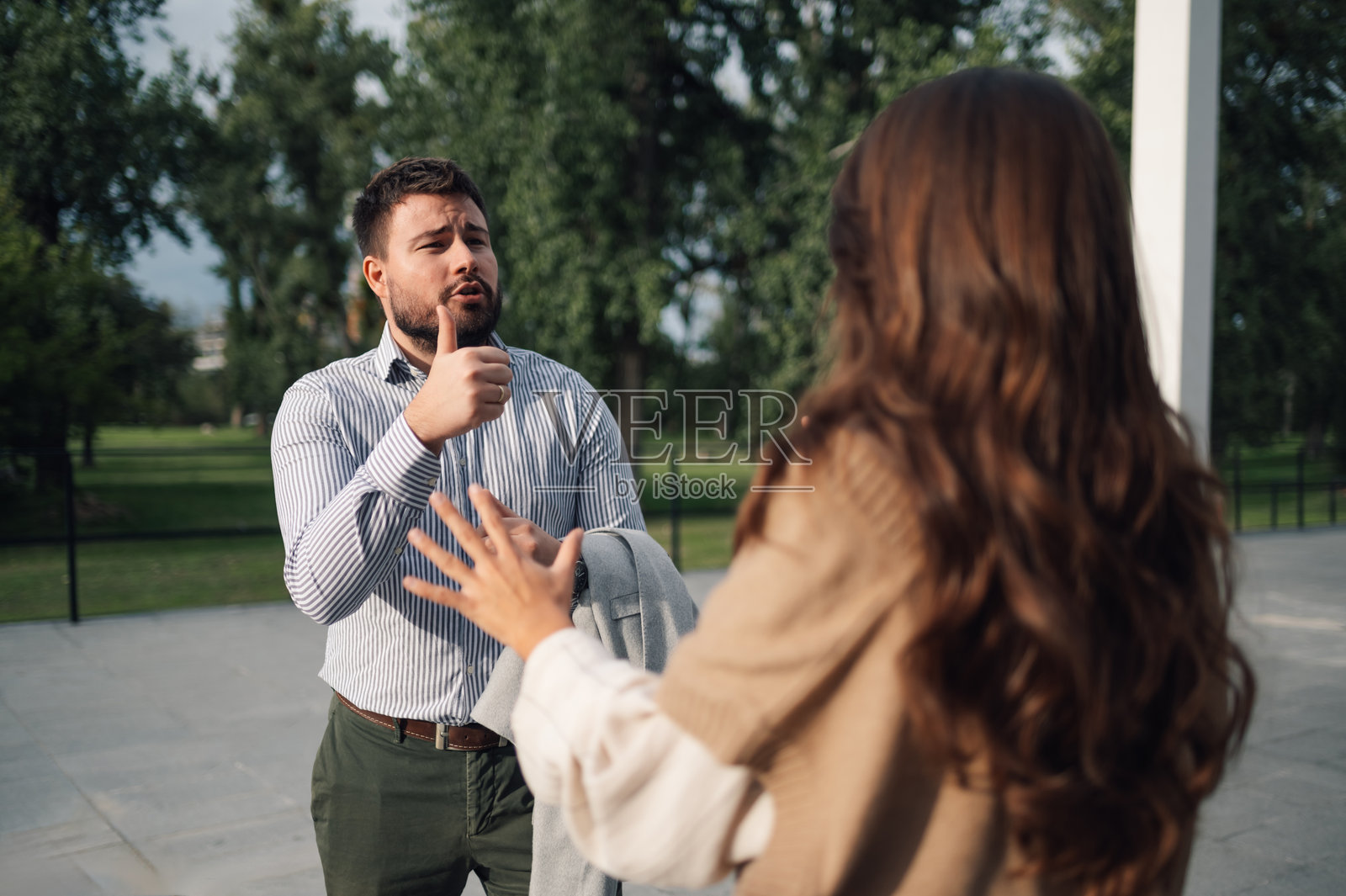 商人在户外与他的女性伙伴交谈时竖起大拇指。照片摄影图片