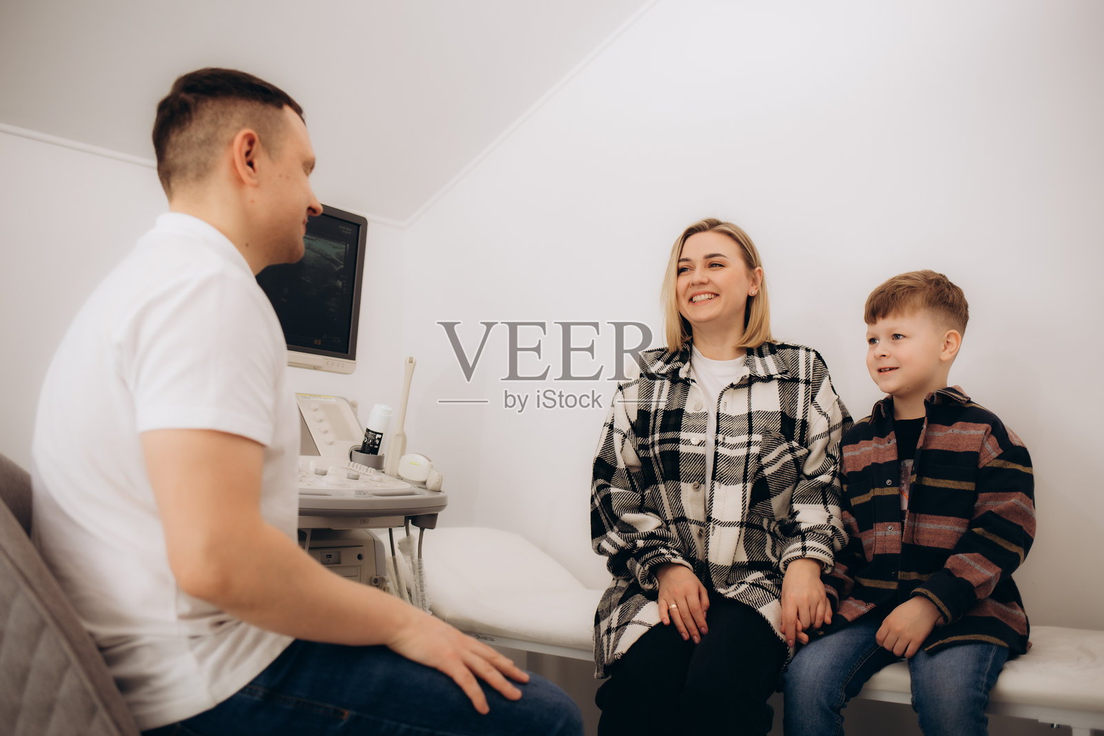 年轻母亲和她的儿子在诊所与医生交谈照片摄影图片