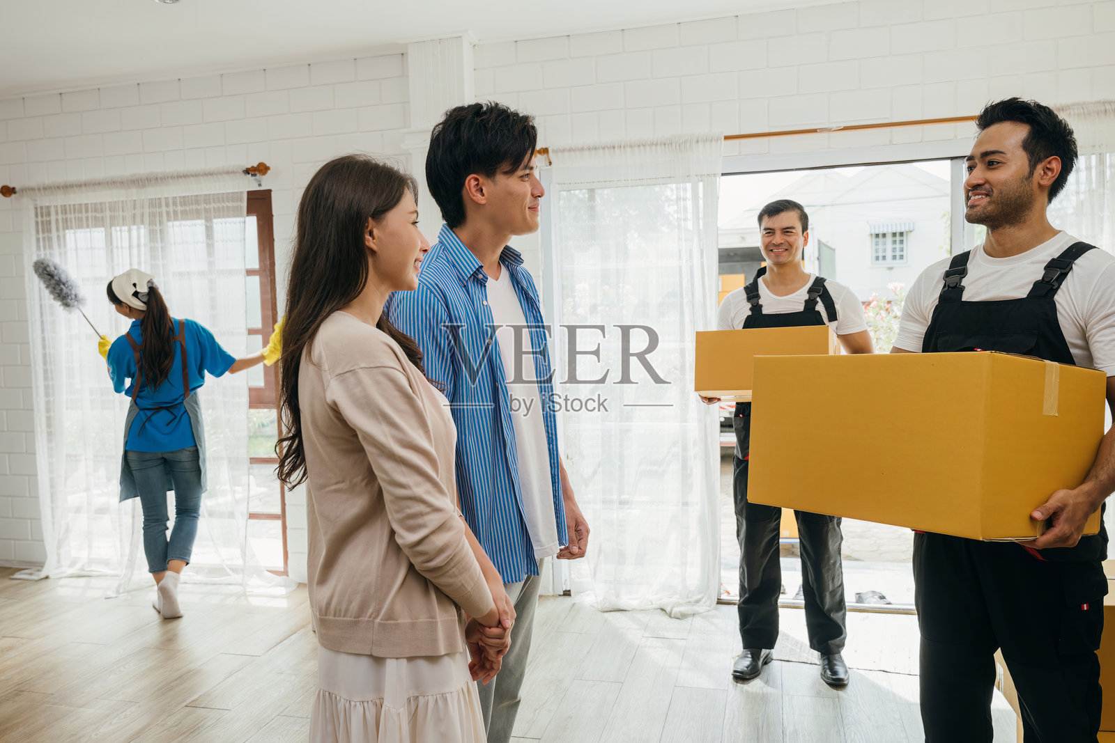 在家中，搬家工人协助一对夫妇从卡车上卸下箱子。专业的搬家服务确保客户在搬迁过程中的满意度。展现了团队合作和高效的工作。搬入新家。照片摄影图片