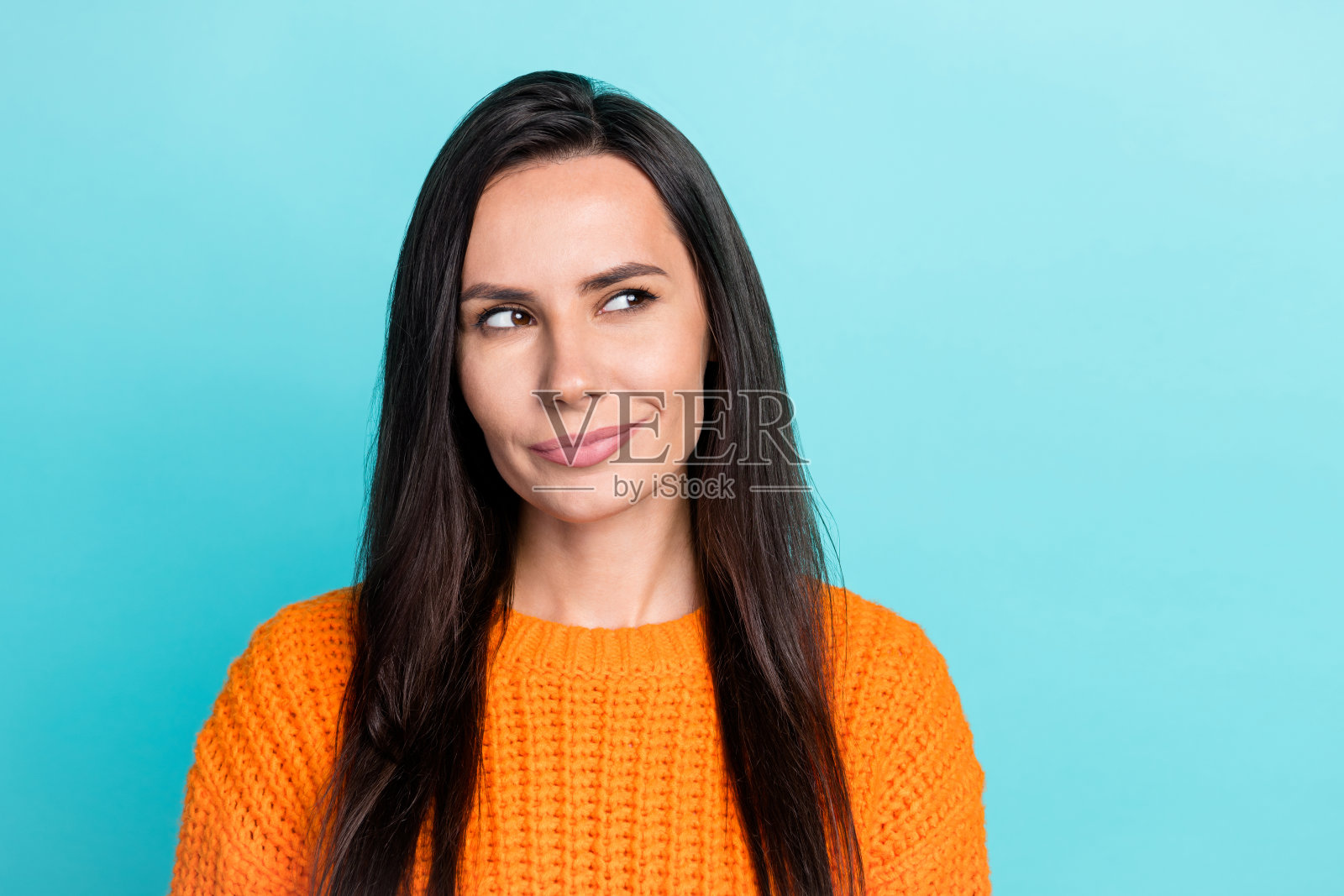 聪明有创意的女孩肖像，目光好奇地凝视空旷的空间，犹豫不决，背景为青绿色。照片摄影图片