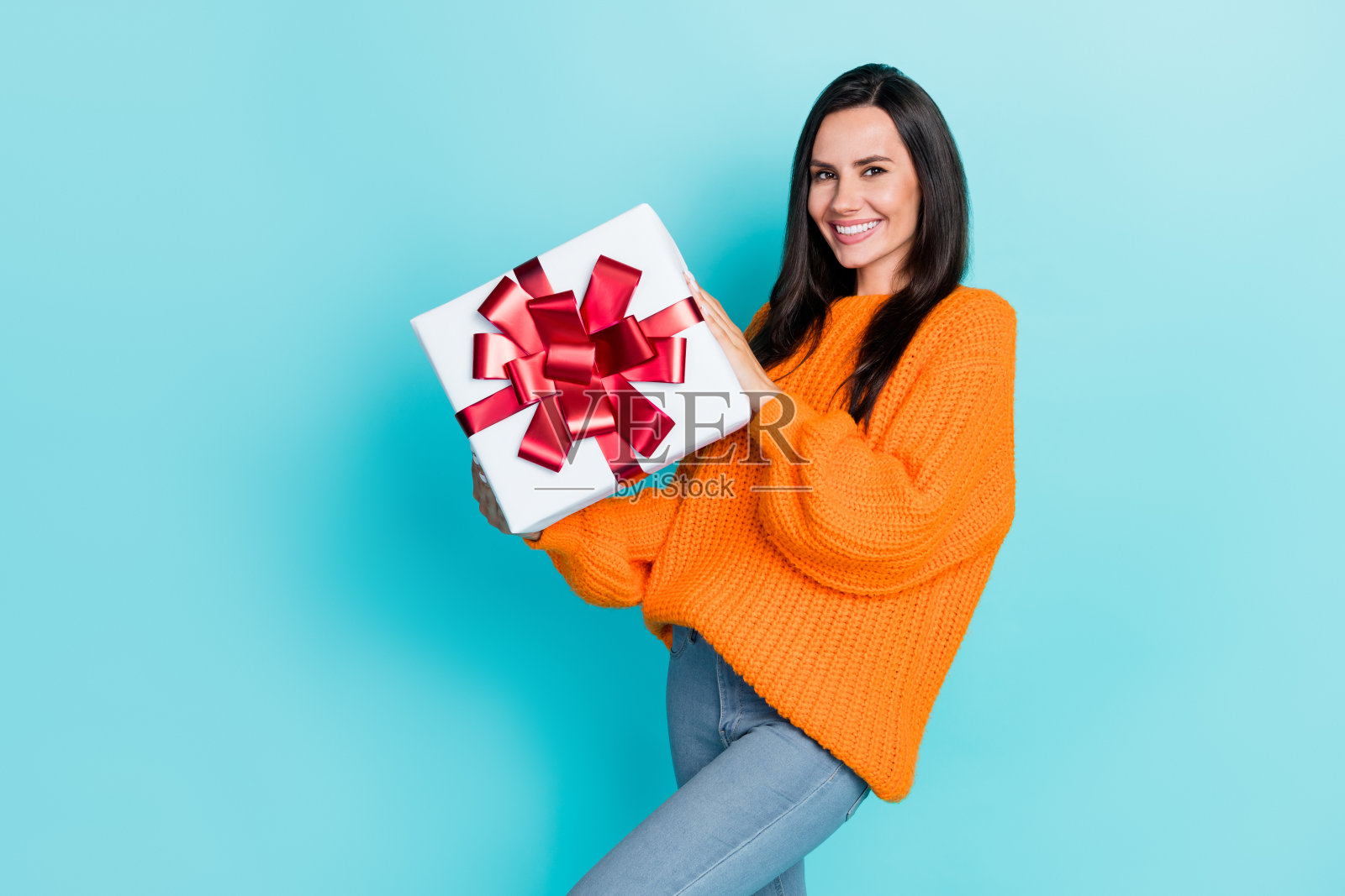 可爱的积极女性微笑着，双手抱着礼盒，背景为水绿色。照片摄影图片