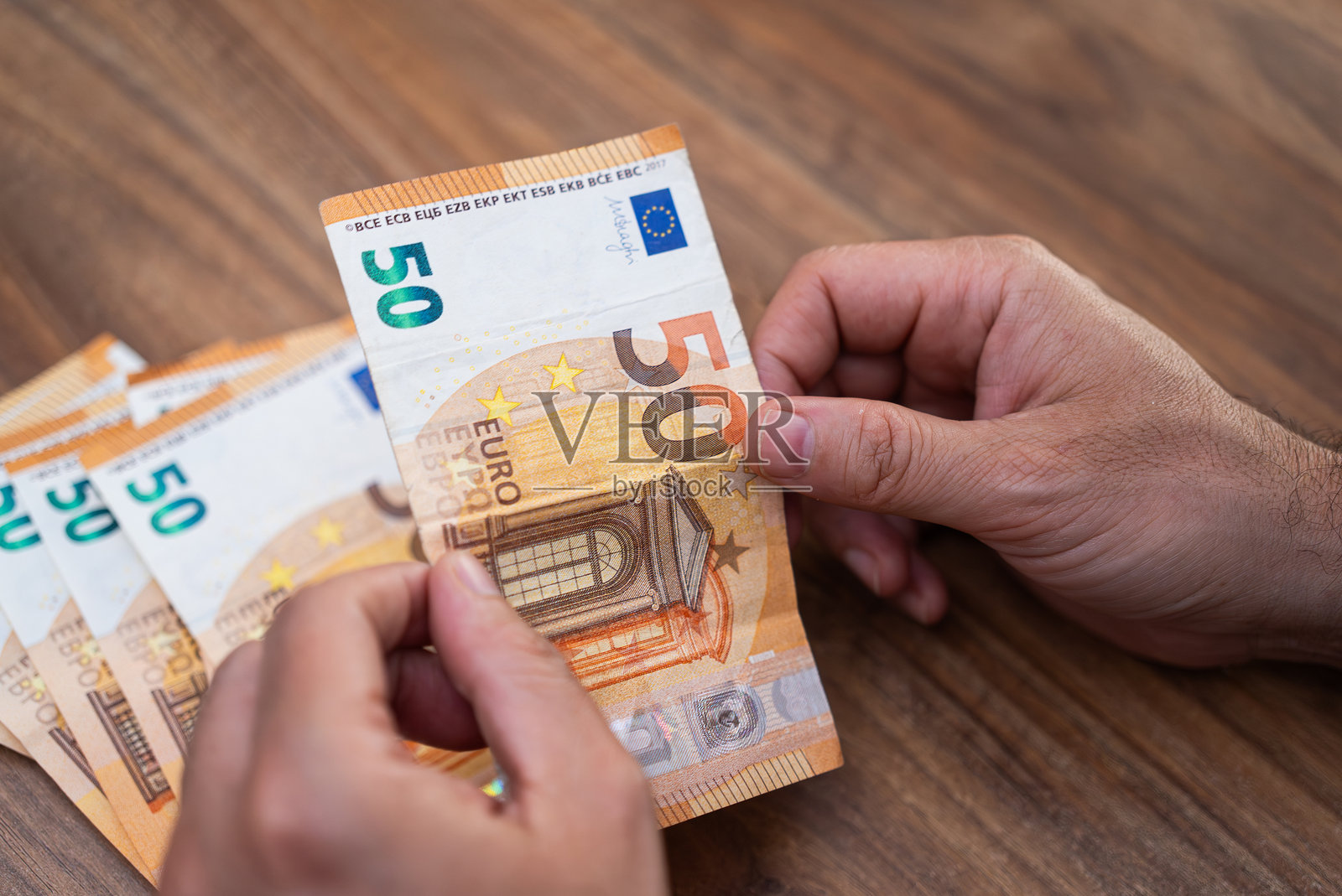 男性企业家手持欧元钞票，正在数钱，享受货币兑换服务的好处。照片摄影图片