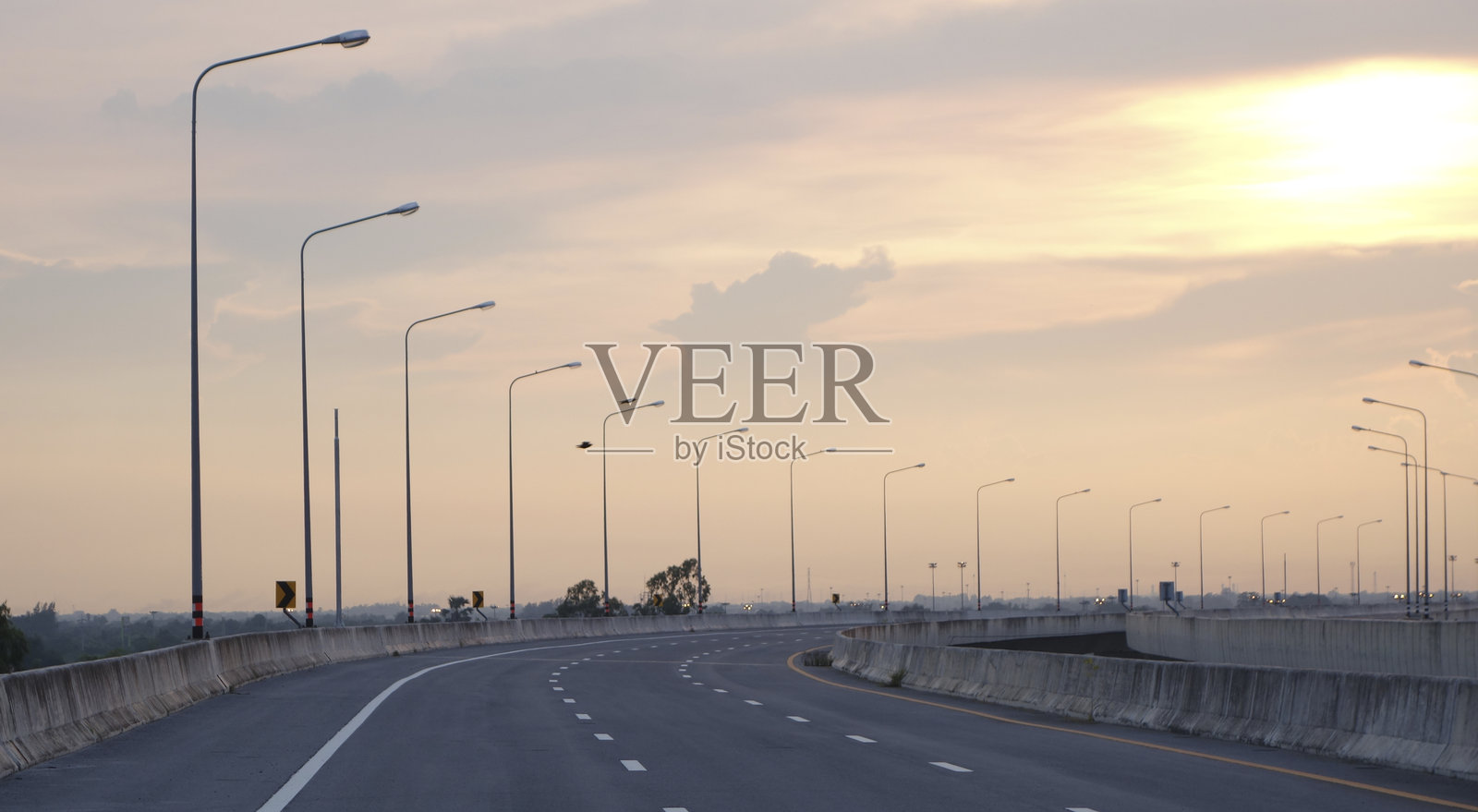 日落时分的城市天际线和山脉，空旷的沥青道路照片摄影图片