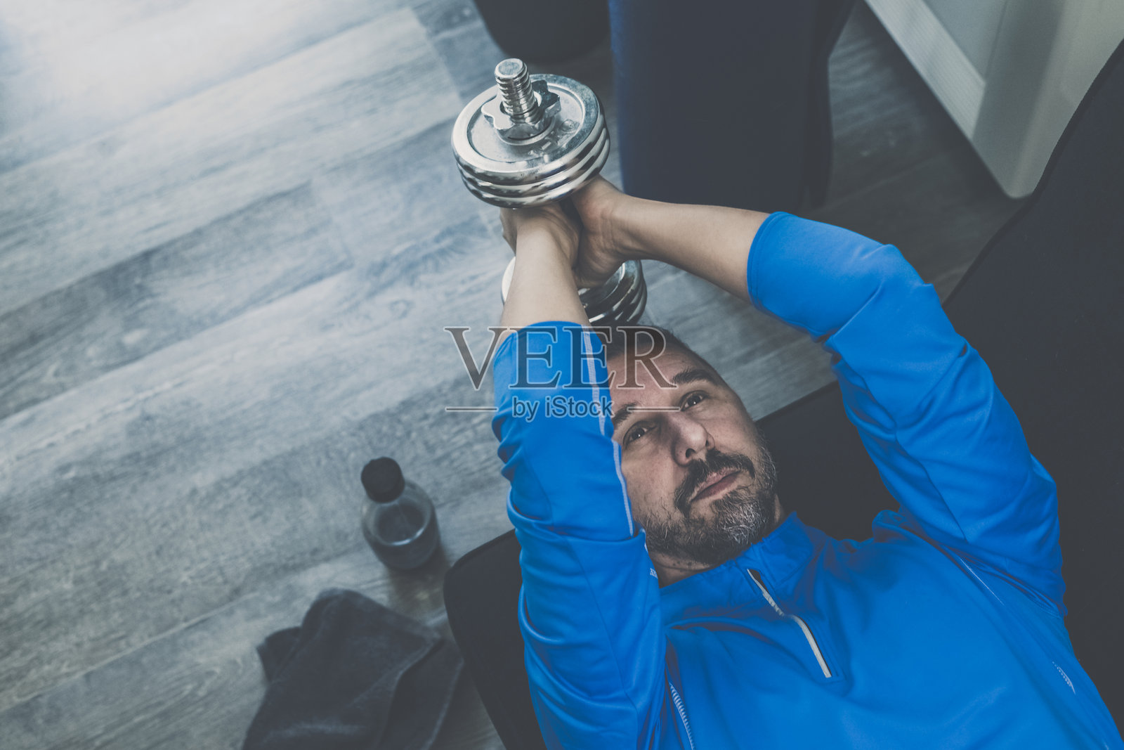 运动男子在家里锻炼和训练。健美男孩在客厅锻炼二头肌。照片摄影图片