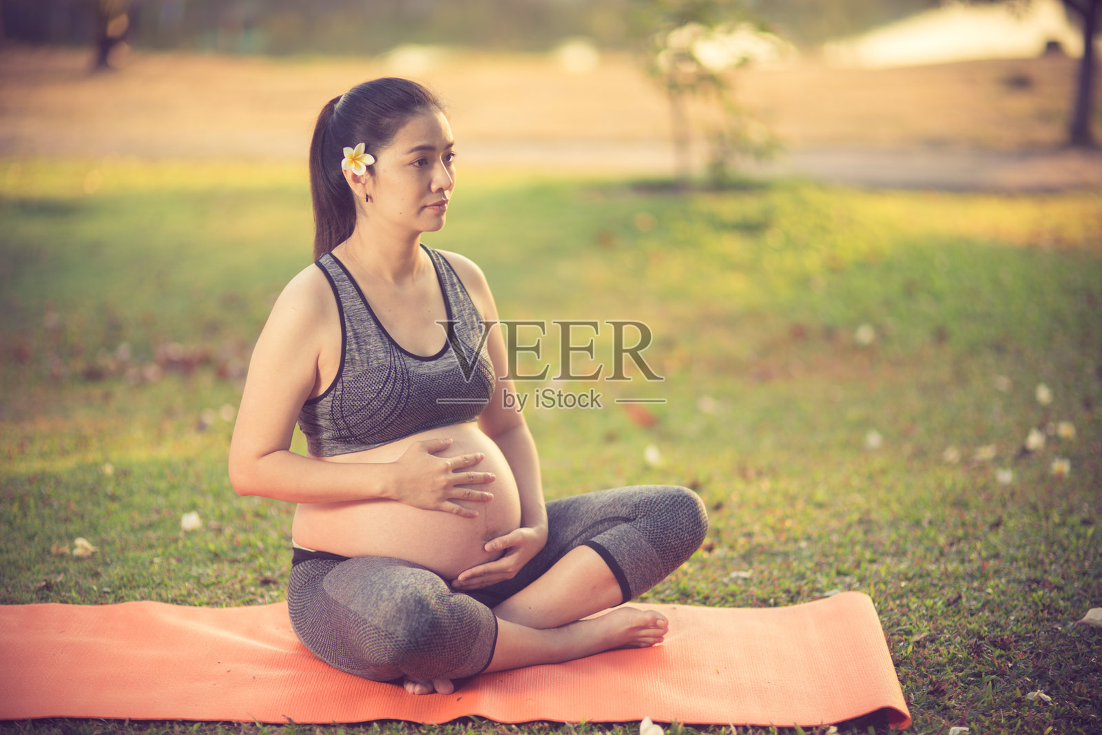微笑的孕妇在田野上做瑜伽照片摄影图片