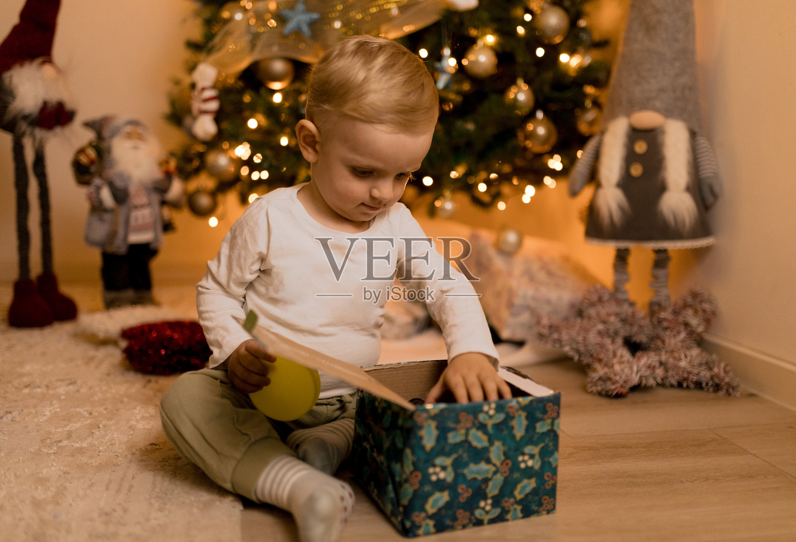 孩子在家中装饰好的圣诞树下打开圣诞礼物照片摄影图片