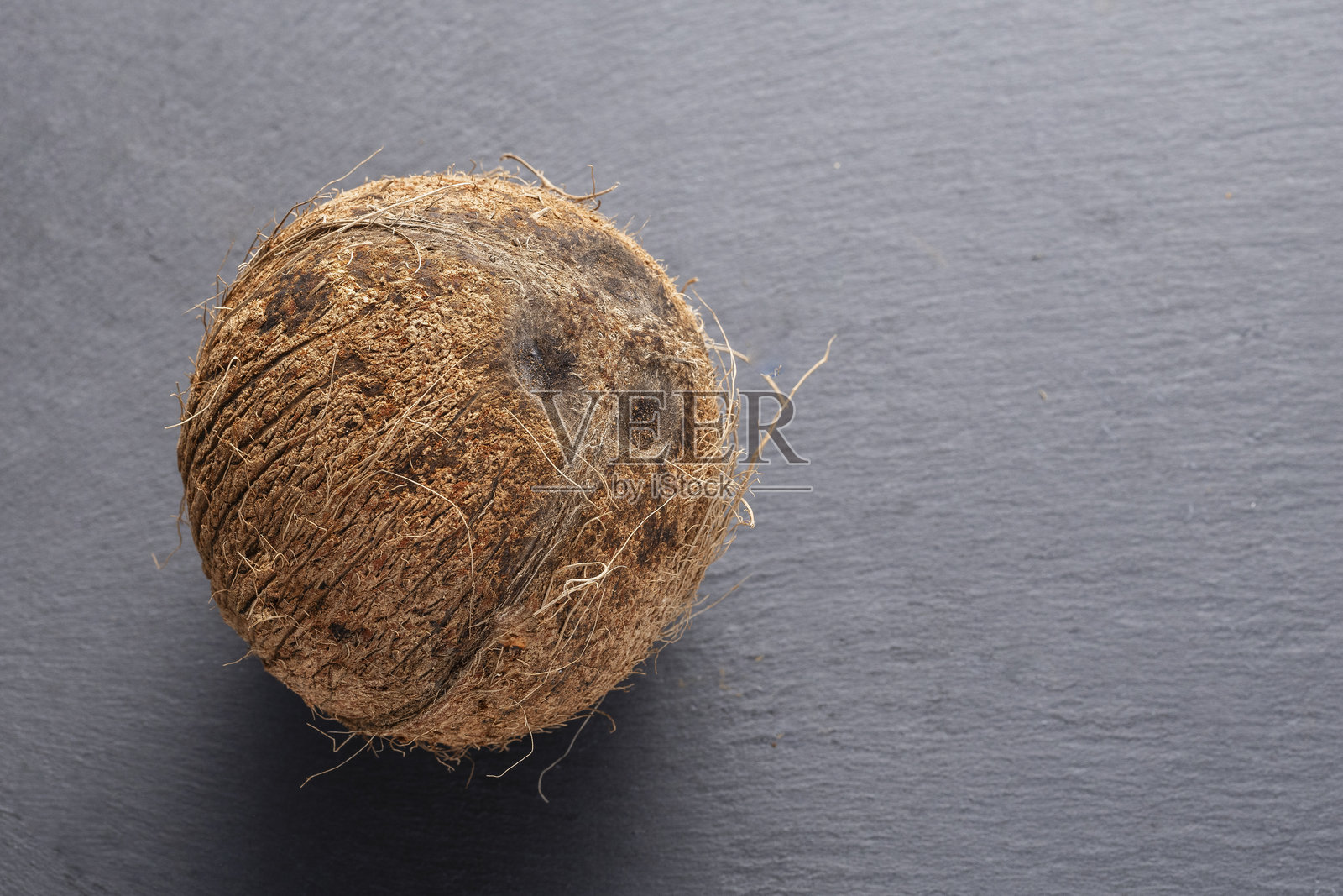 一颗椰子果实放在石头表面上照片摄影图片