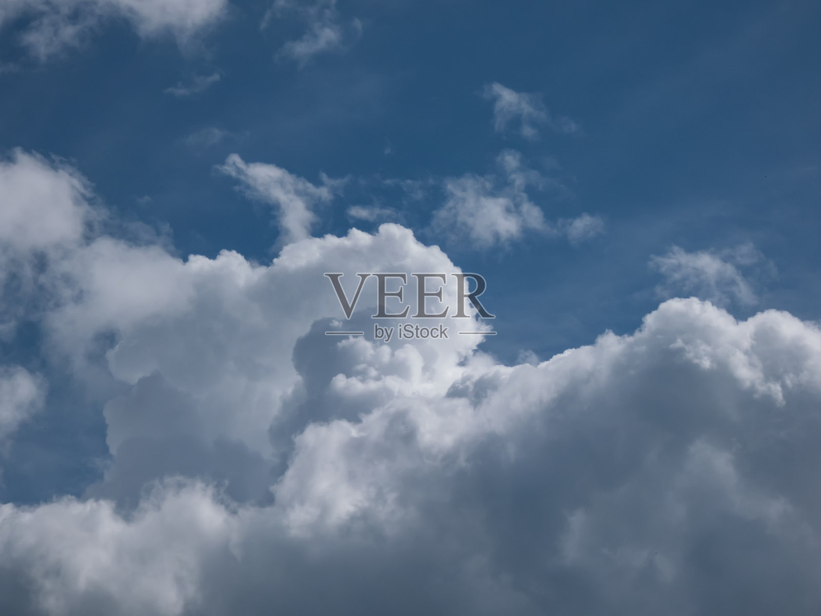 阳光明媚的日子里，蓝天上飘着蓬松的白云。阳光照耀下的黑暗天空与美丽的白云。照片摄影图片