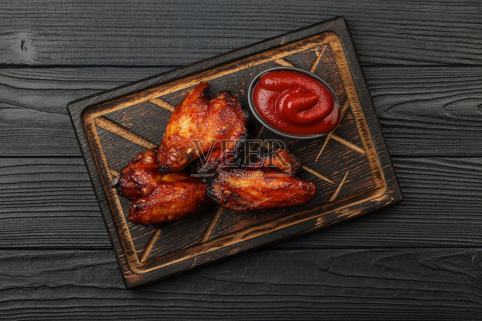 美味的烤鸡翅搭配辣酱，摆放在木板上照片摄影图片
