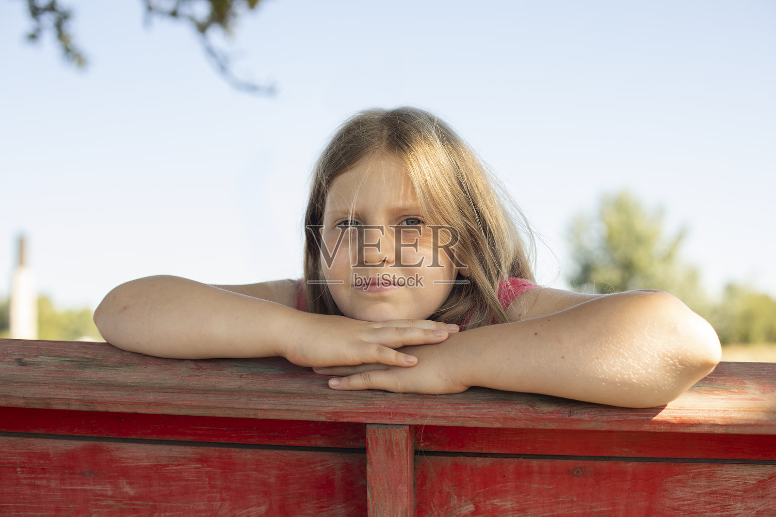 金发的9岁女孩在阳光明媚的夏日里，双手托着下巴，特写肖像。照片摄影图片