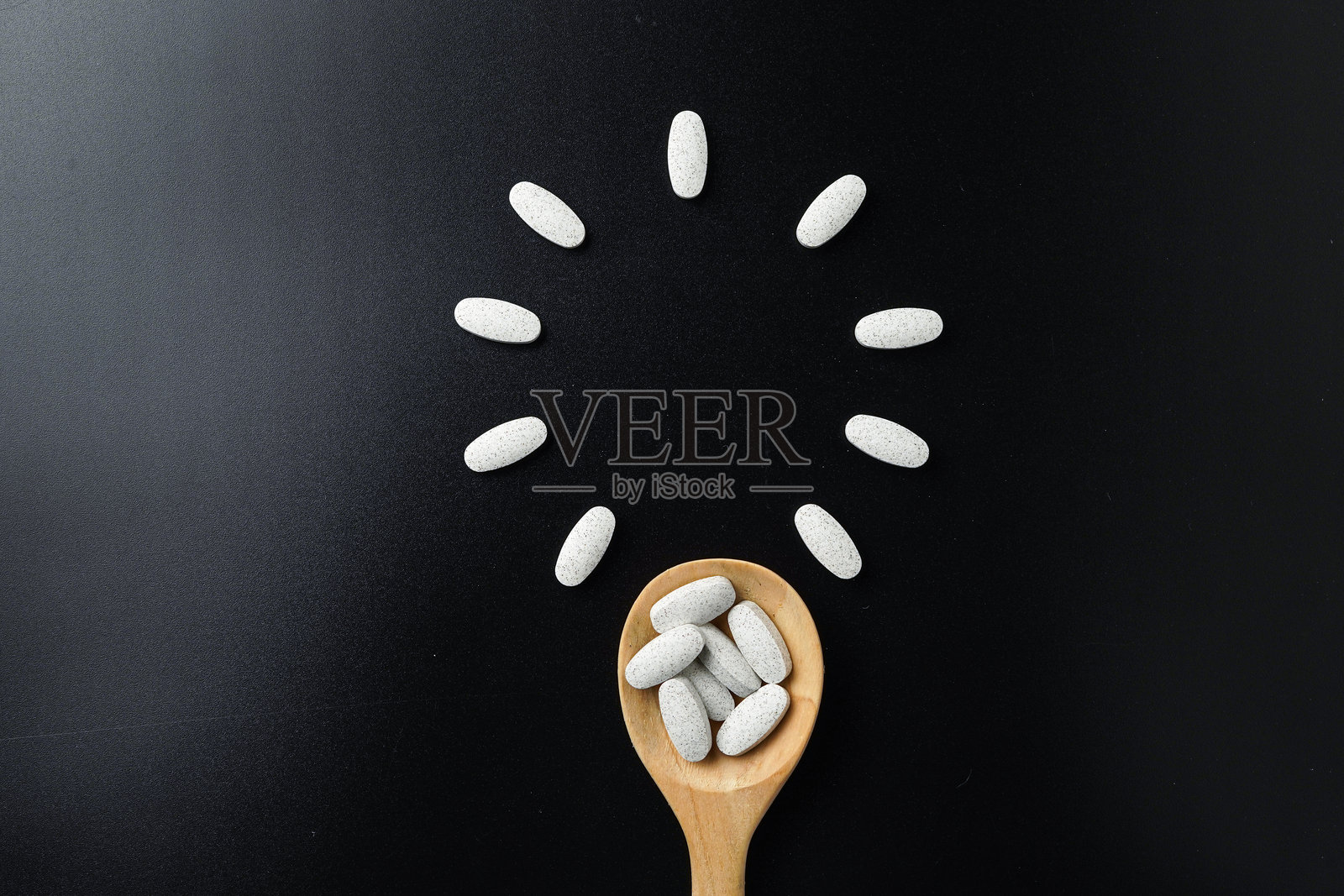 黑色背景上的木勺中装有白色药丸、药片和胶囊的泡罩包装。照片摄影图片
