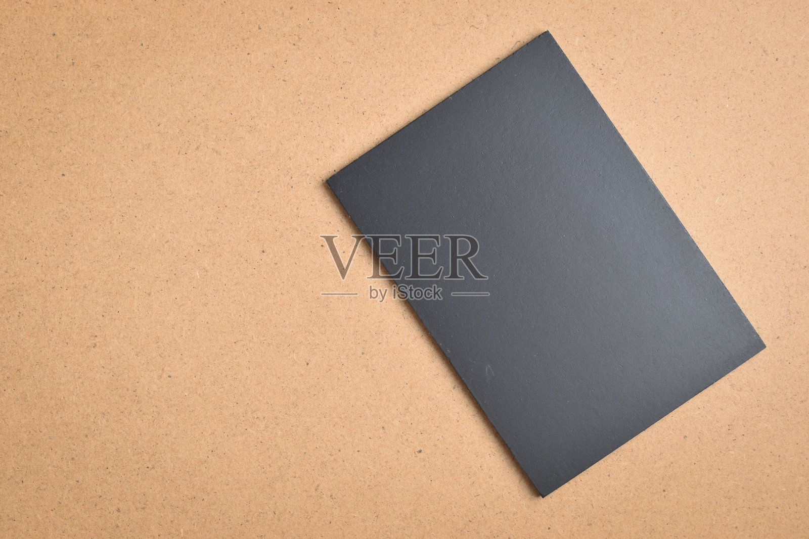 黑色空白笔记本放在棕色木纹背景上照片摄影图片