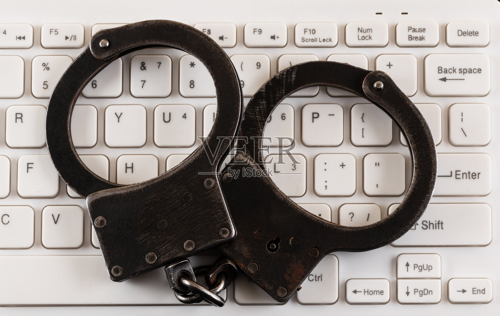 黑色钢制手铐放在电脑键盘上照片摄影图片