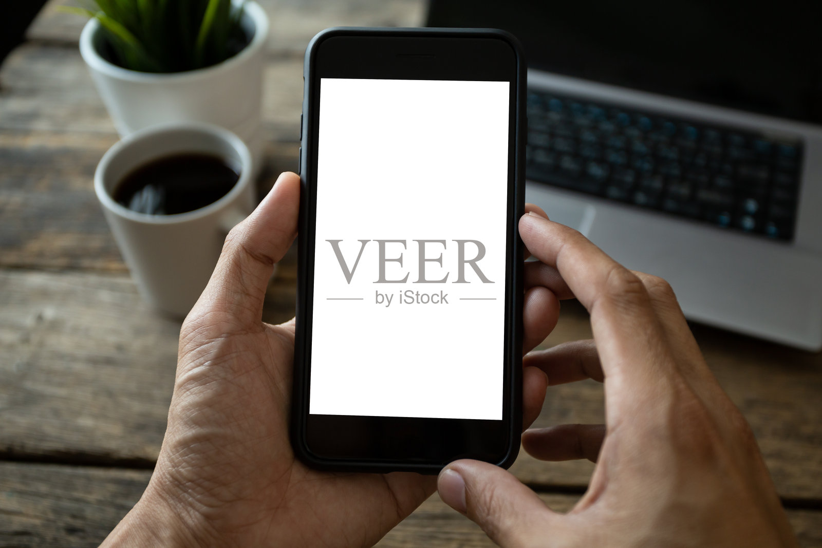 咖啡店里，男人用手拿着智能手机，屏幕空白，带有剪切路径。照片摄影图片