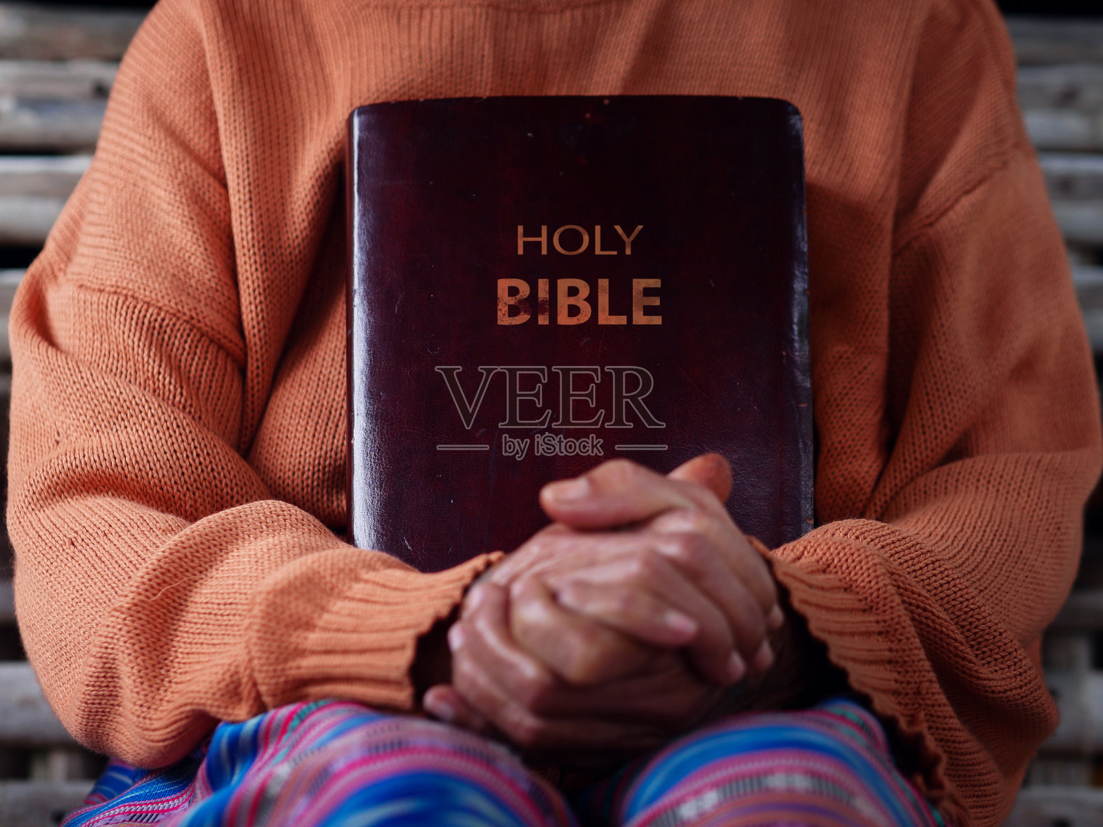 一位基督教女性抱着圣经，双手合十祈祷，象征着希望。照片摄影图片