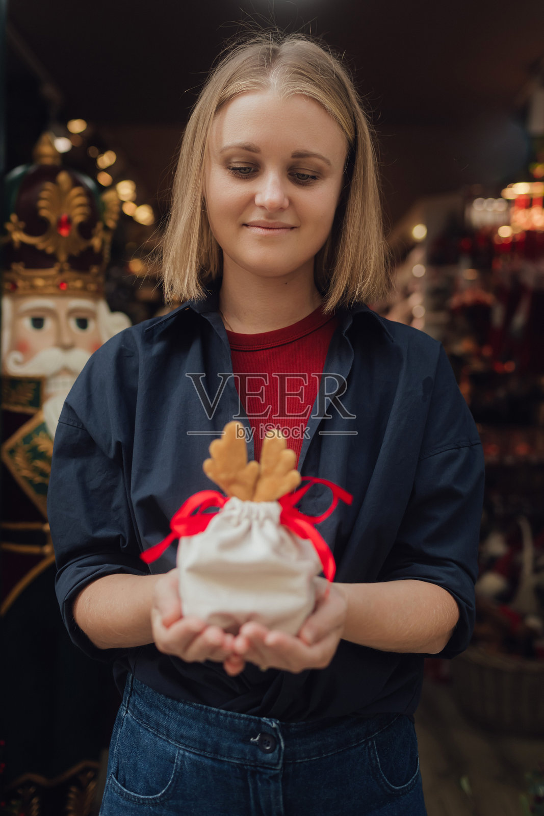 年轻快乐的女人手里拿着礼物，背景是一个圣诞礼品店。假日购物的概念。系列的一部分。照片摄影图片