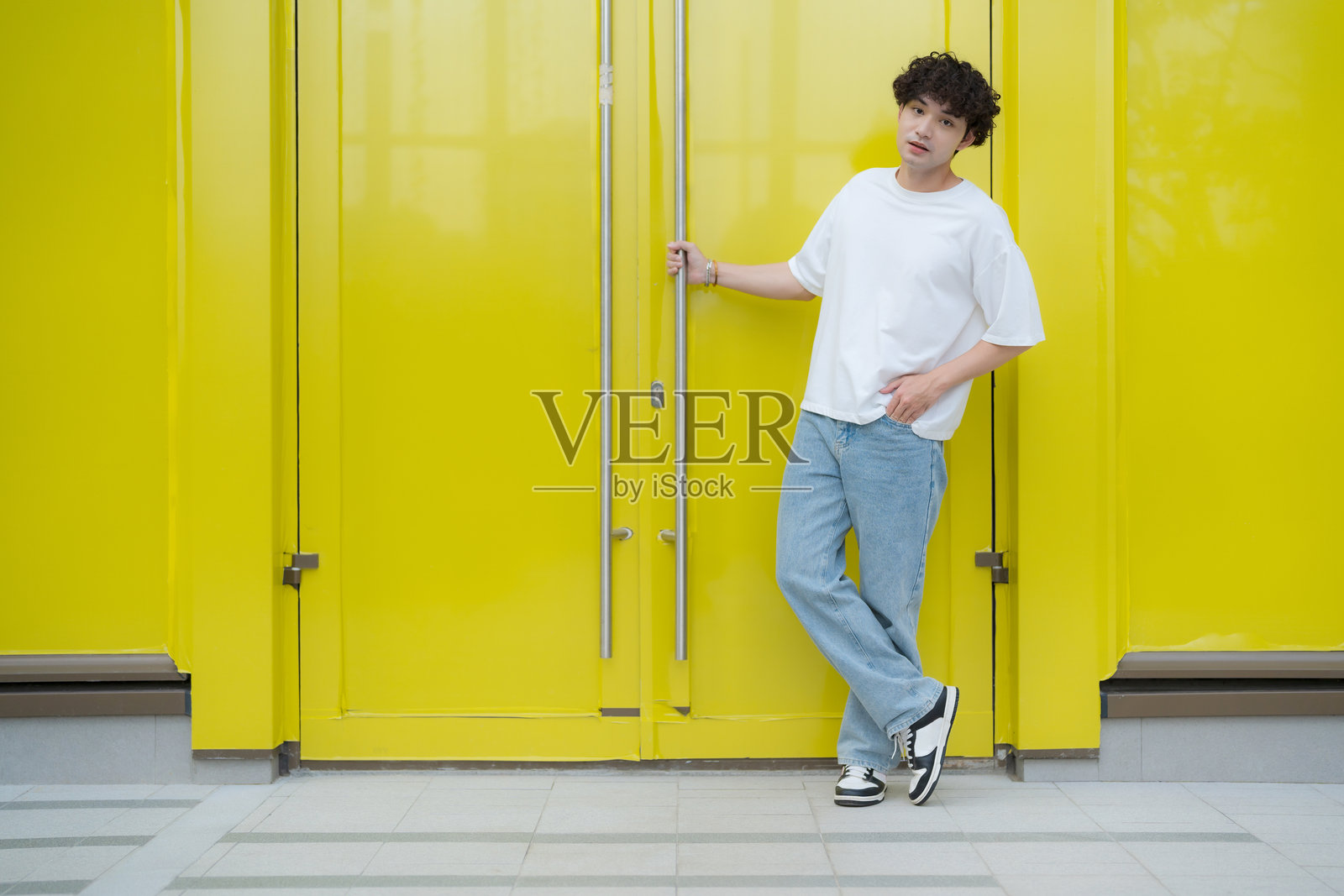 年轻男子在鲜艳的黄色门旁摆姿势照片摄影图片