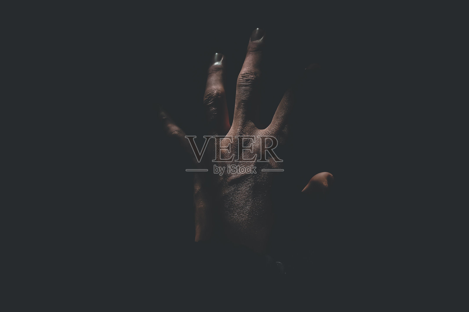 男性手在黑色背景中伸向黑暗中的光。手部聚焦。照片摄影图片