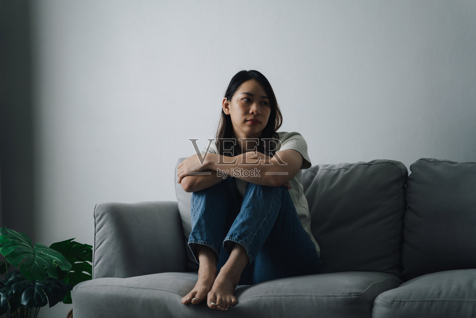 不快乐、孤独、沮丧的女人坐在沙发上。她看起来悲伤而疲惫。照片摄影图片