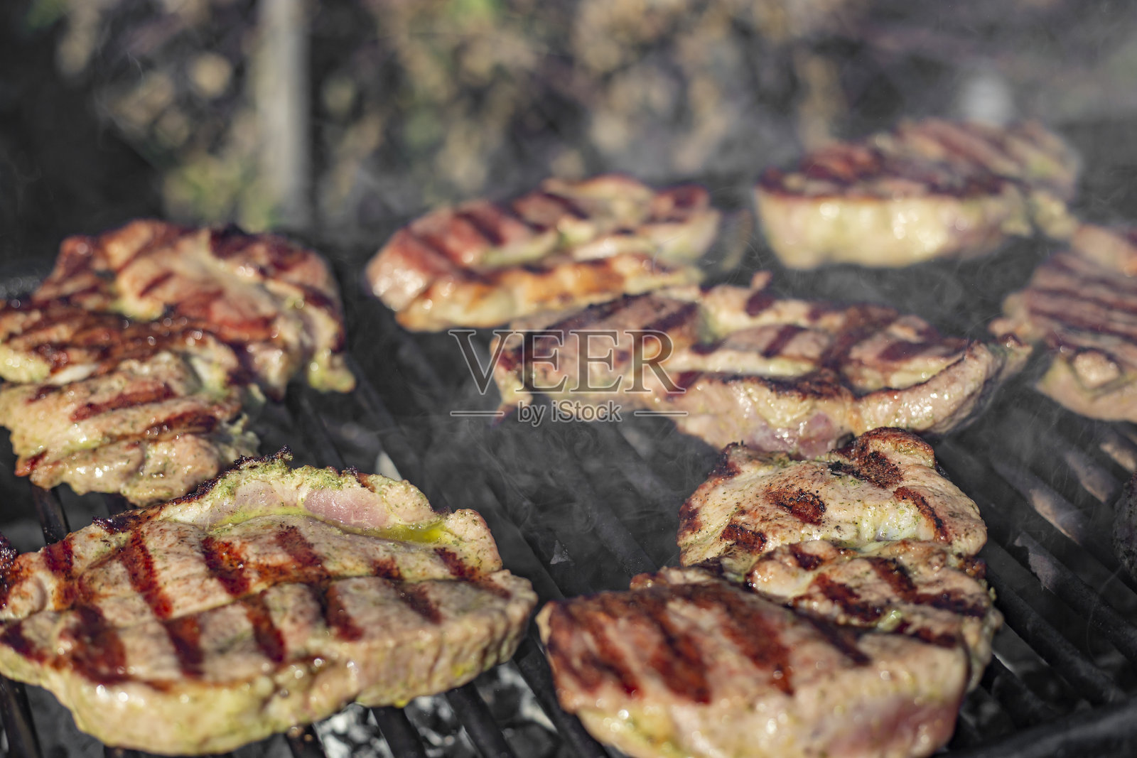 腌制的猪颈肉和猪肩肉片在户外烟熏烤制，柔焦特写侧视图照片摄影图片