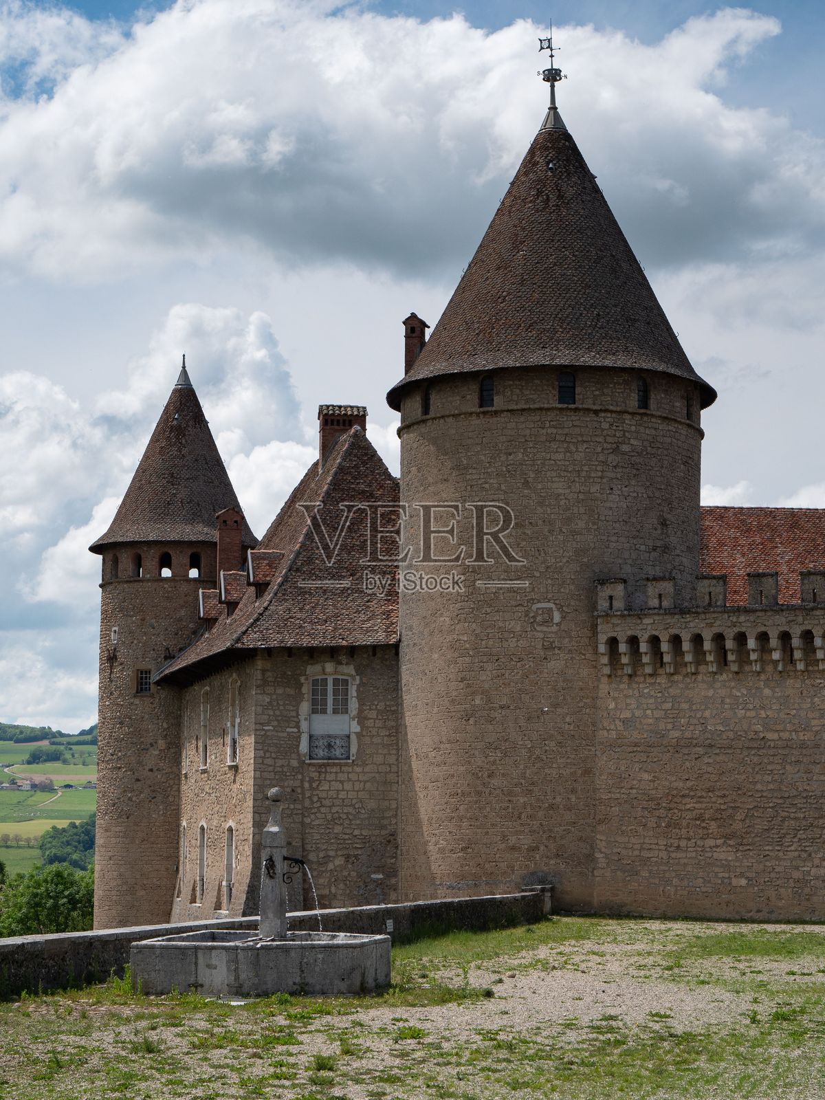 在乡村风景中，云雾弥漫的天空下，维里厄城堡的圆锥形塔楼的垂直视角。照片摄影图片