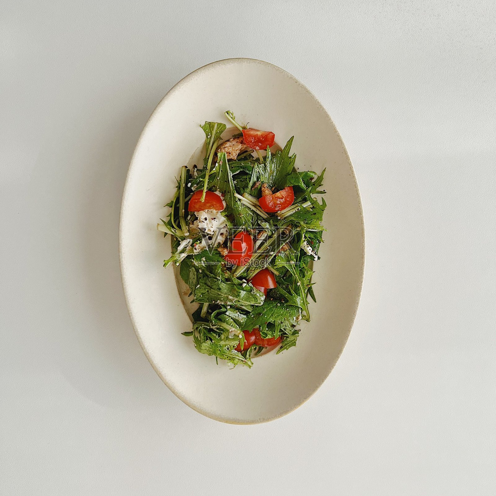 新鲜的蔬菜沙拉，色彩斑斓的绿叶、樱桃番茄、黄瓜和甜椒混合在一起。清脆、丰富多彩，富含维生素，这道沙拉是健康美味的主菜或配菜。照片摄影图片