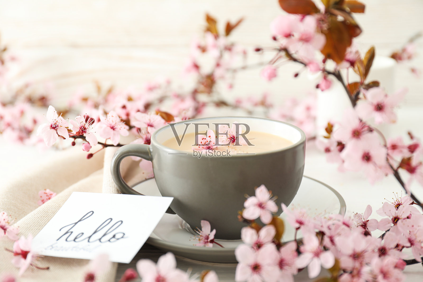 春天的花枝与一杯热饮，背景为浅色木纹。照片摄影图片