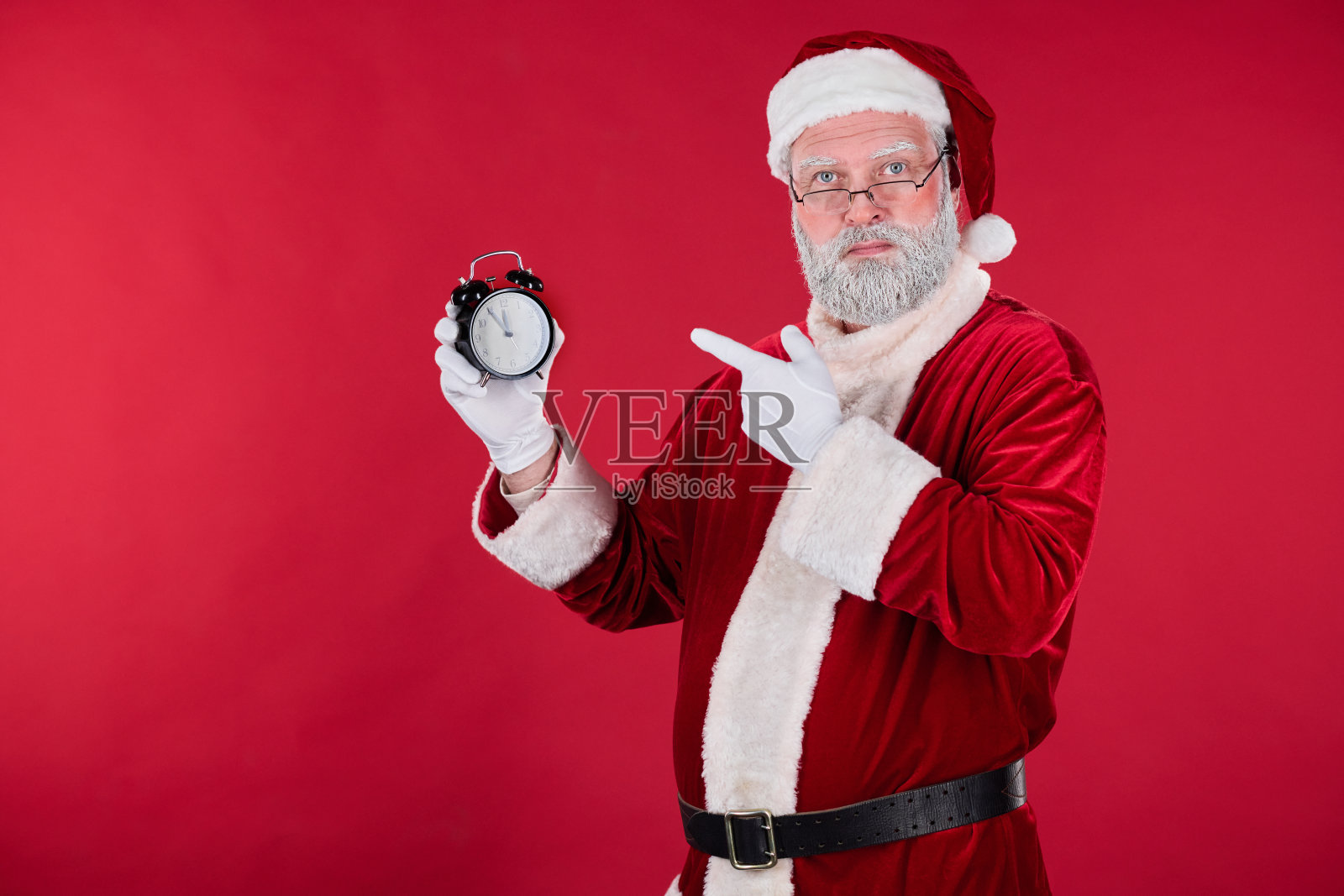 拿着时钟的圣诞老人穿着传统红色套装照片摄影图片