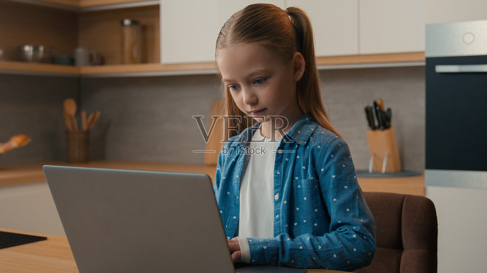 白人女孩独自在家厨房使用笔记本电脑，通过社交媒体进行交流，打字、浏览、玩游戏，学习互联网教育，使用电脑技术。照片摄影图片