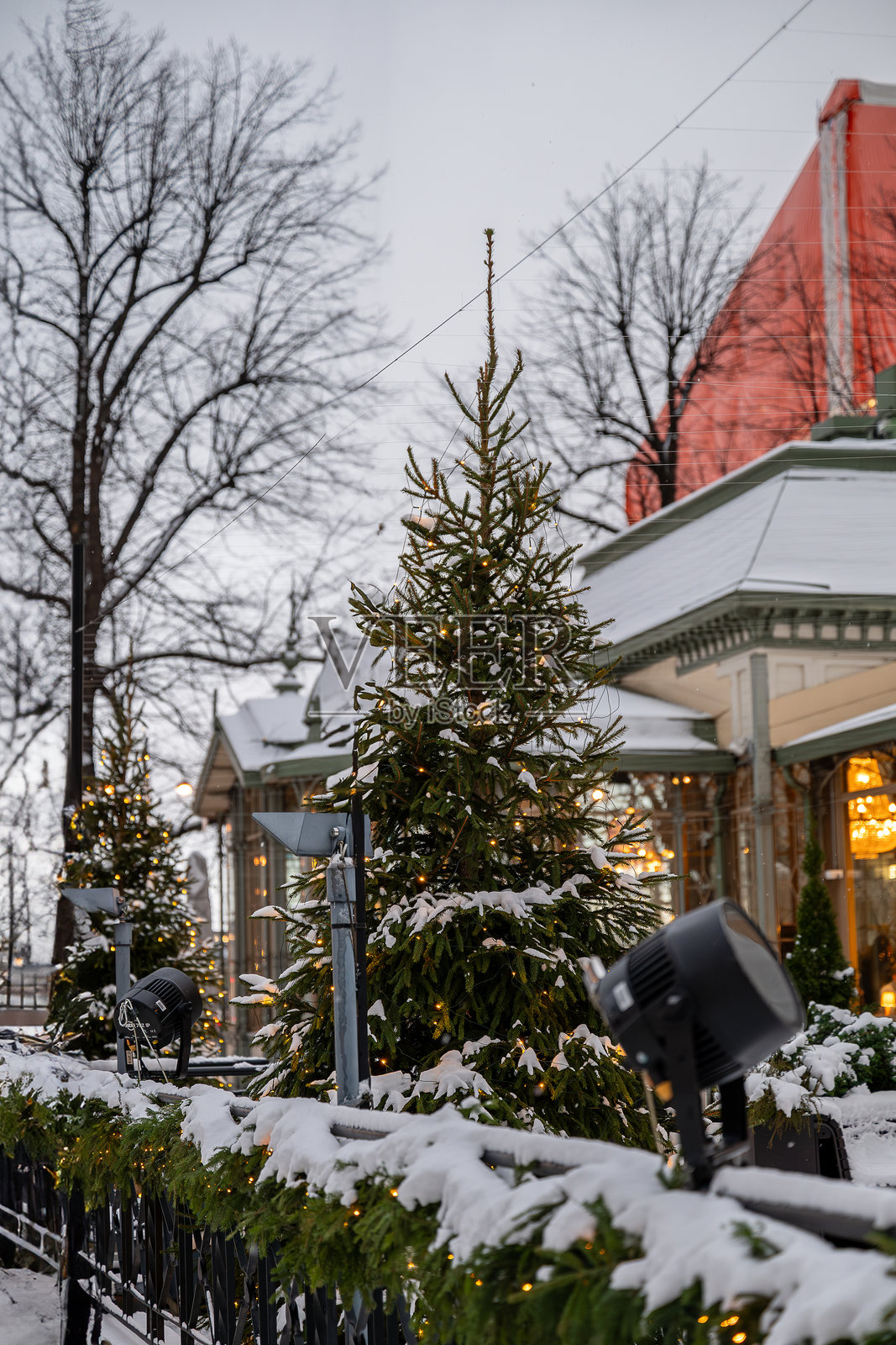 装饰着温暖灯光的雪白圣诞树，靠近一座传统建筑照片摄影图片