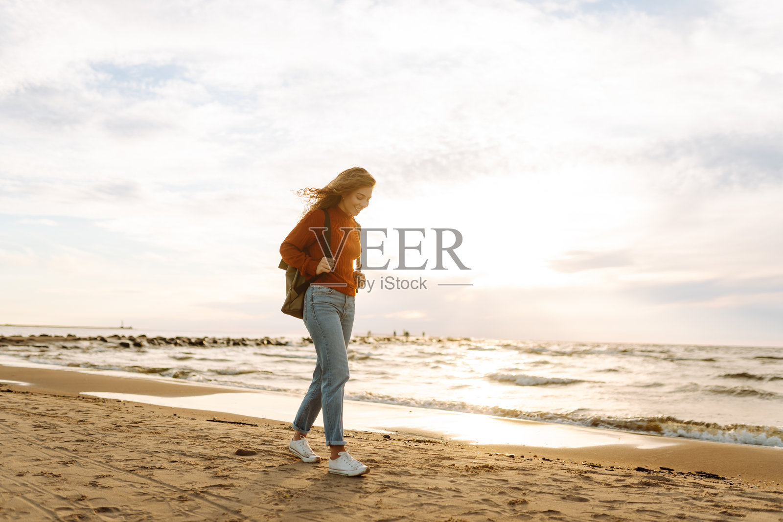 日落时分，海滩上美丽女性的肖像。照片摄影图片