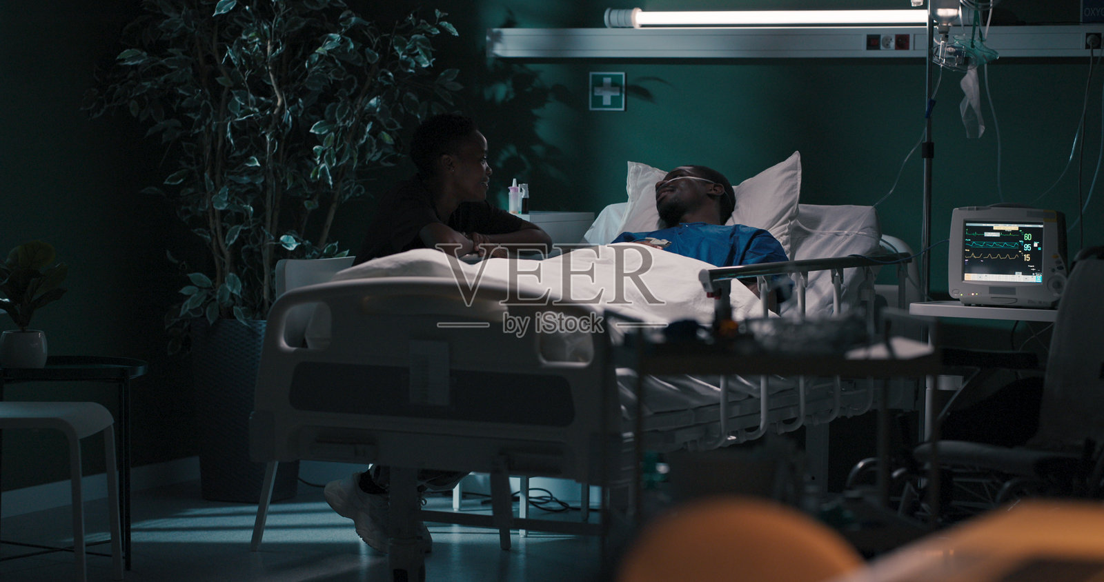 非洲情侣在医院分享一个时刻，男友戴着氧气面罩，女友陪伴在旁。照片摄影图片