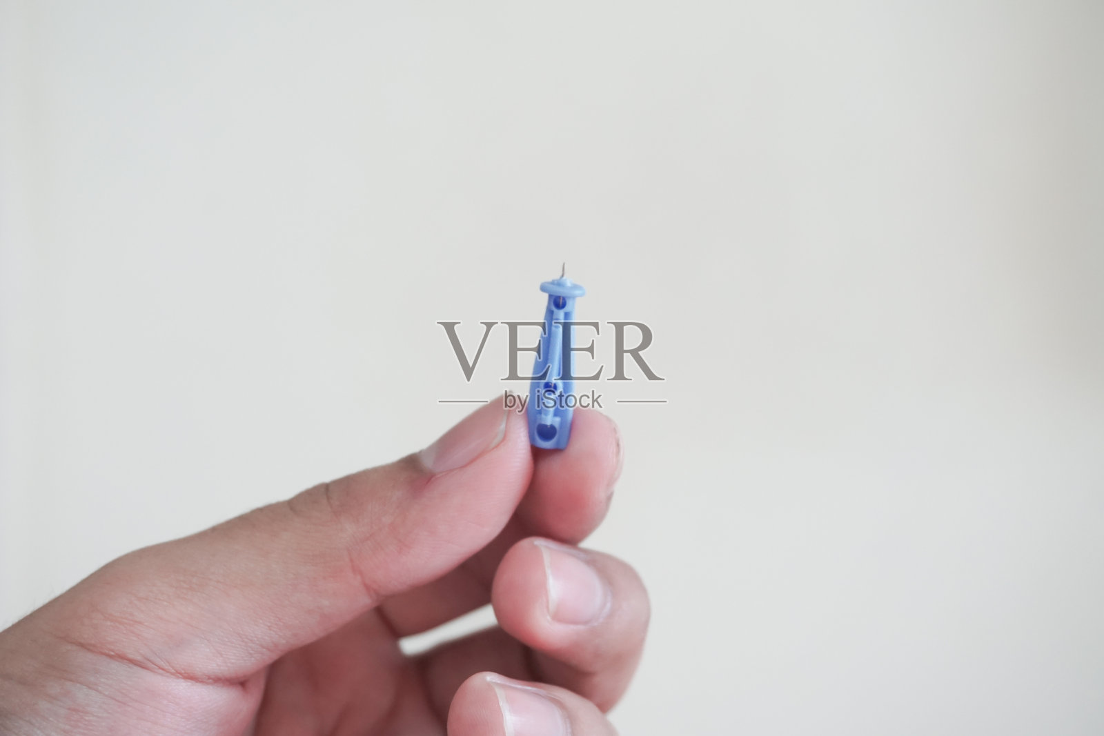 医生的手握着血糖针刺入人类食指以检测血糖，背景为白色，并使用路径处理。照片摄影图片