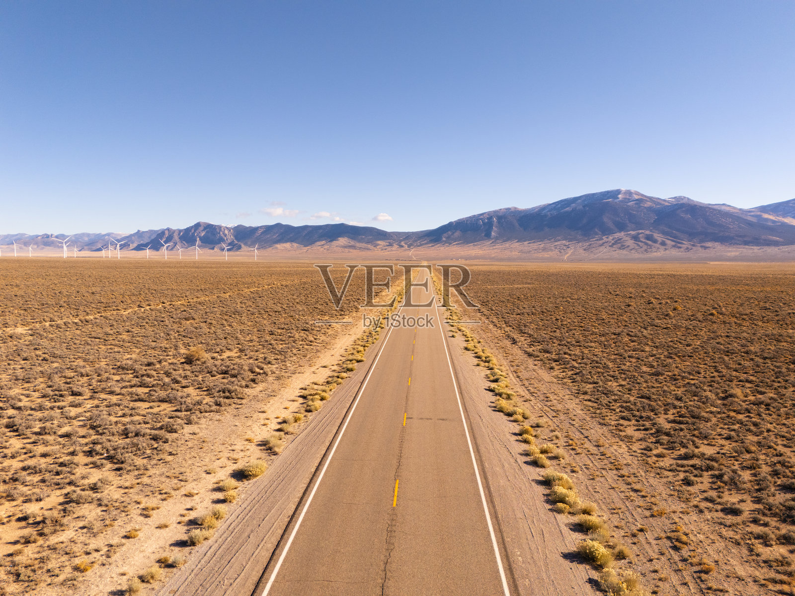 美国50号公路的鸟瞰图，这是美国最孤独的公路，以及内华达州的风车公园，高原沙漠和被雪覆盖的山脉。晴朗的蓝天。照片摄影图片