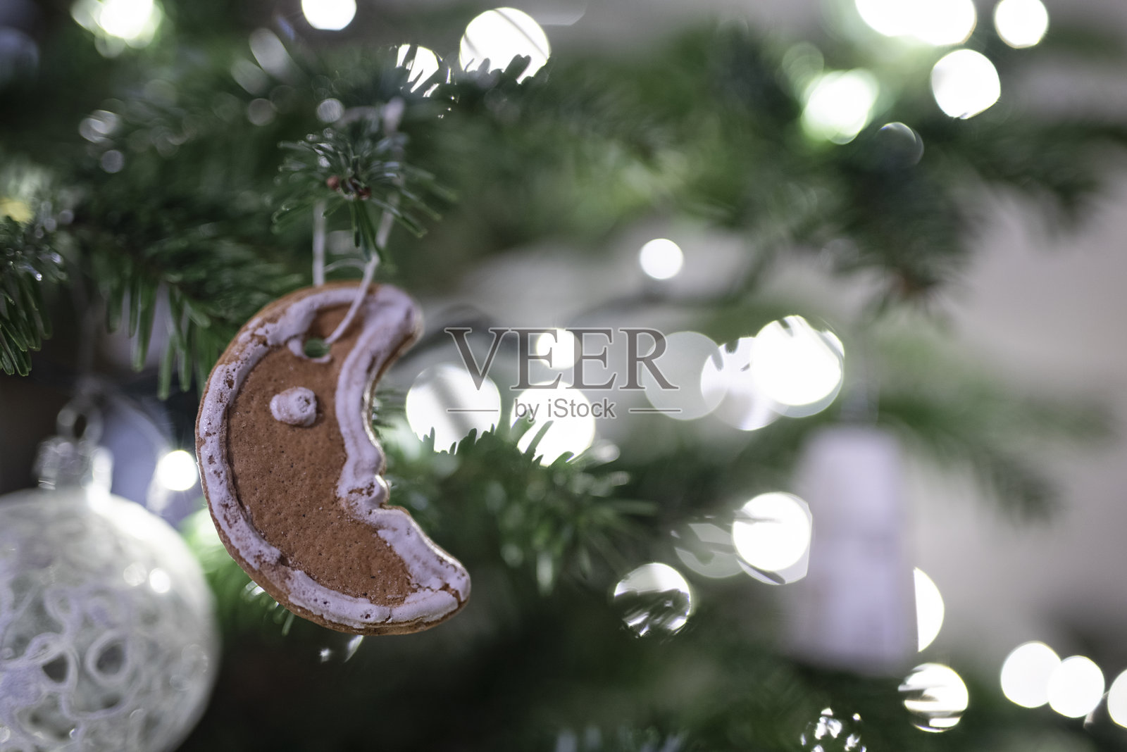 挂在圣诞树上的姜饼蛋糕，闪亮的仙女灯光装饰。圣诞装饰。照片摄影图片