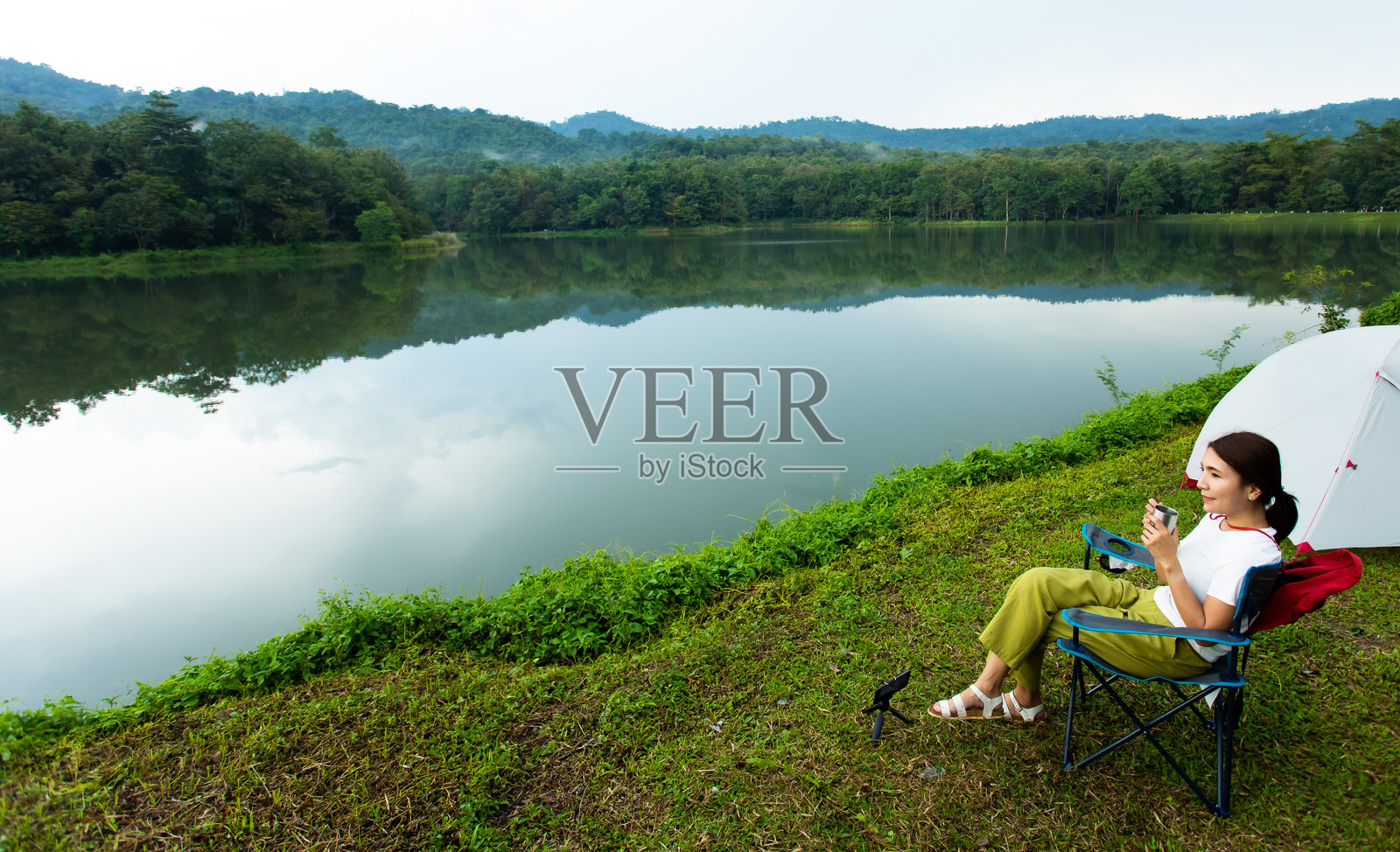 坐在湖边椅子上的女人手握杯子照片摄影图片